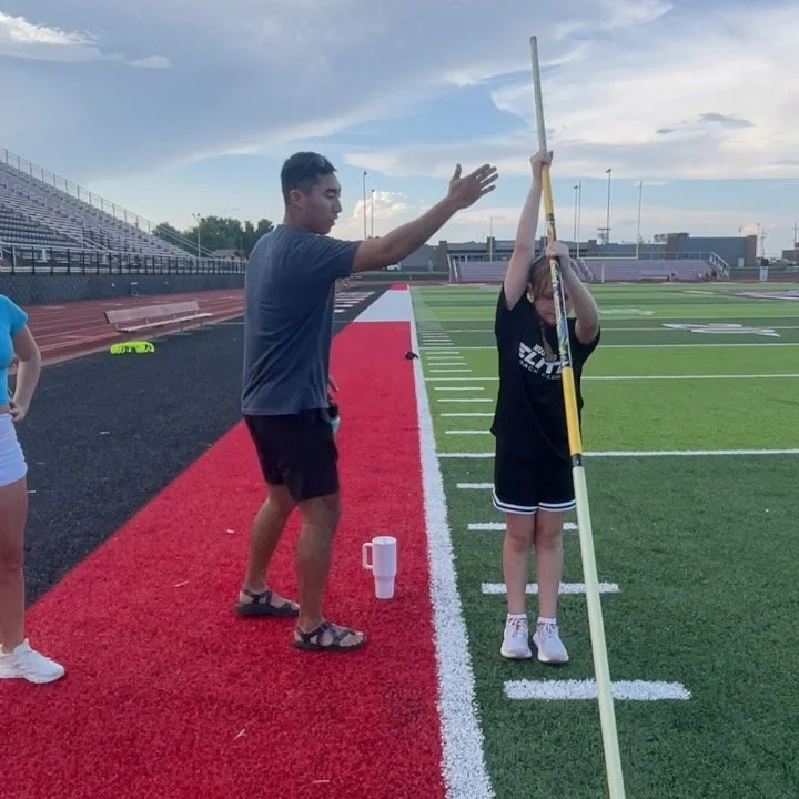 Coach Roush instructs a girl on pole vaulting