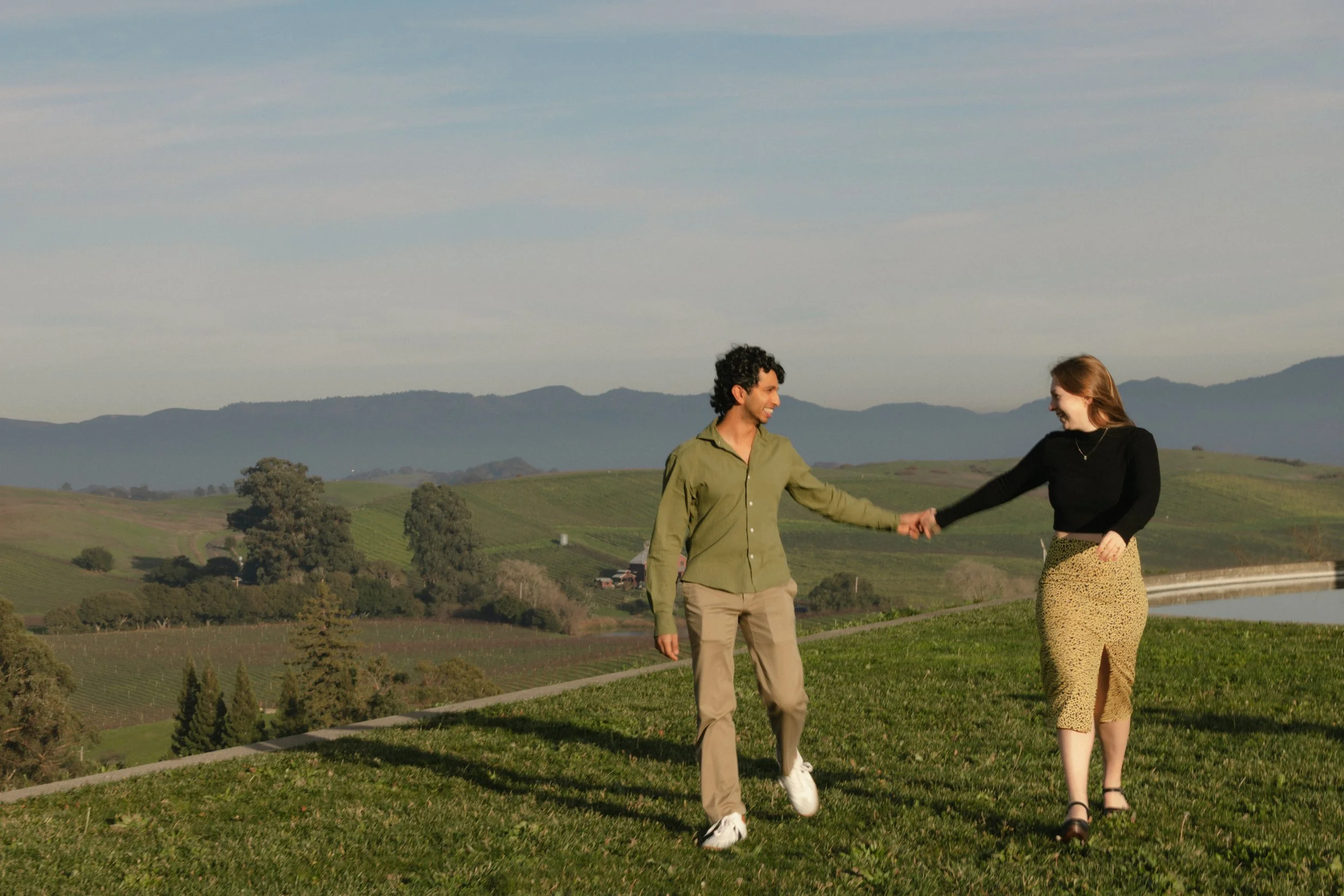 Newly engaged couple strolling through vineyards in Napa Valley following their proposal at Artesa in Napa Valley.