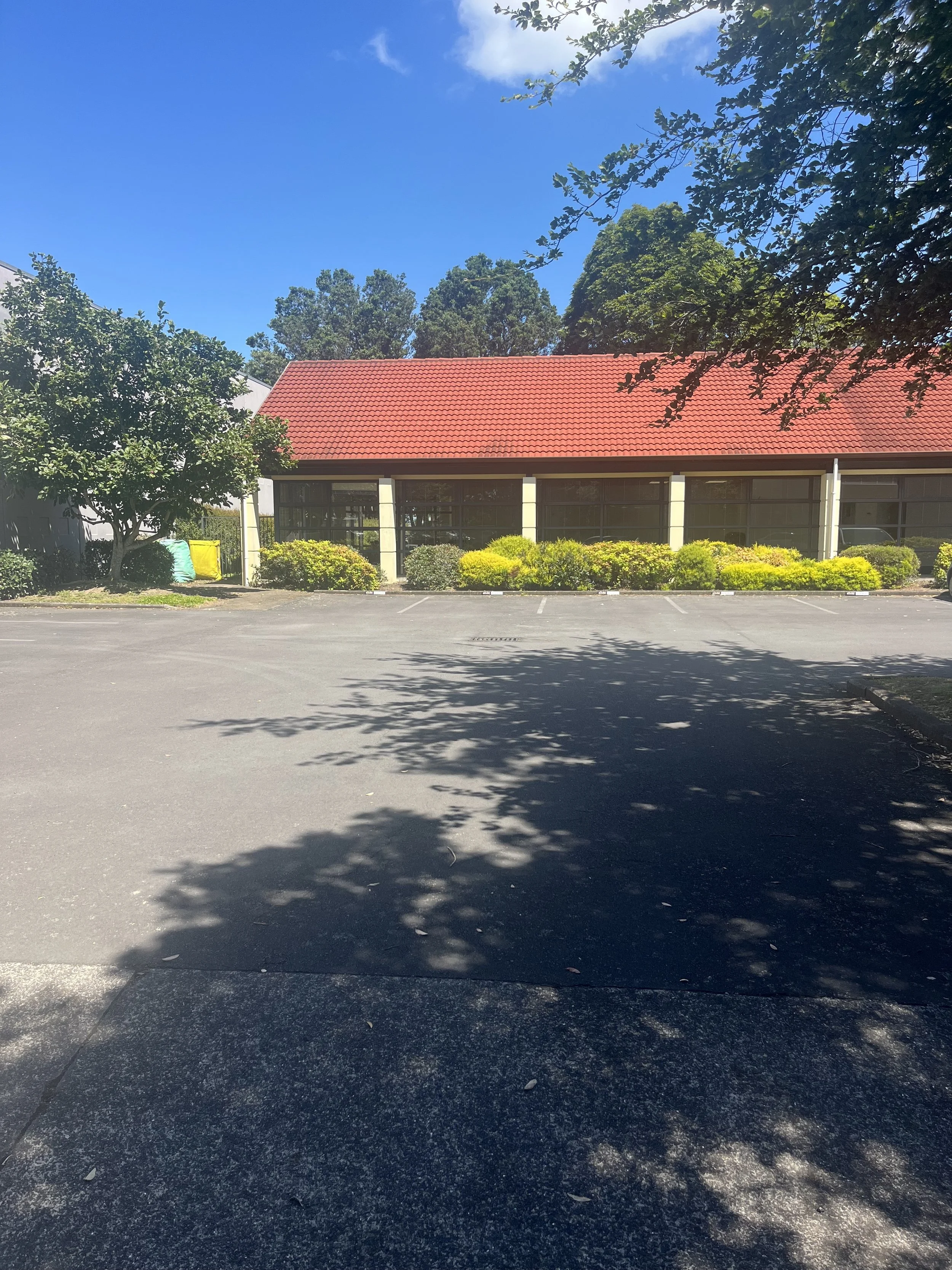 Carparks with a yellow brick building with a red roof in the background.