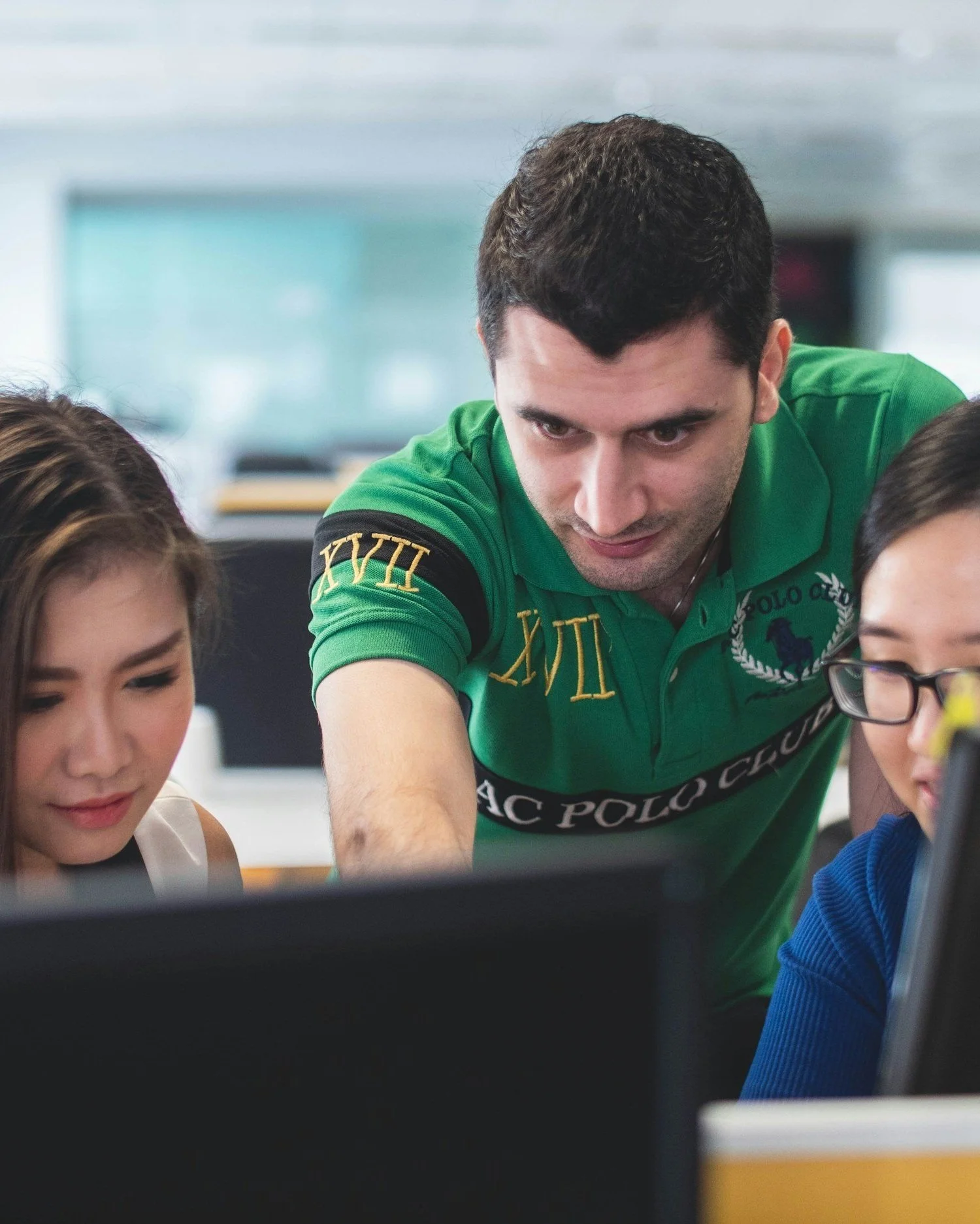 Group of people collaborating in an office environment, focusing on computer screens.