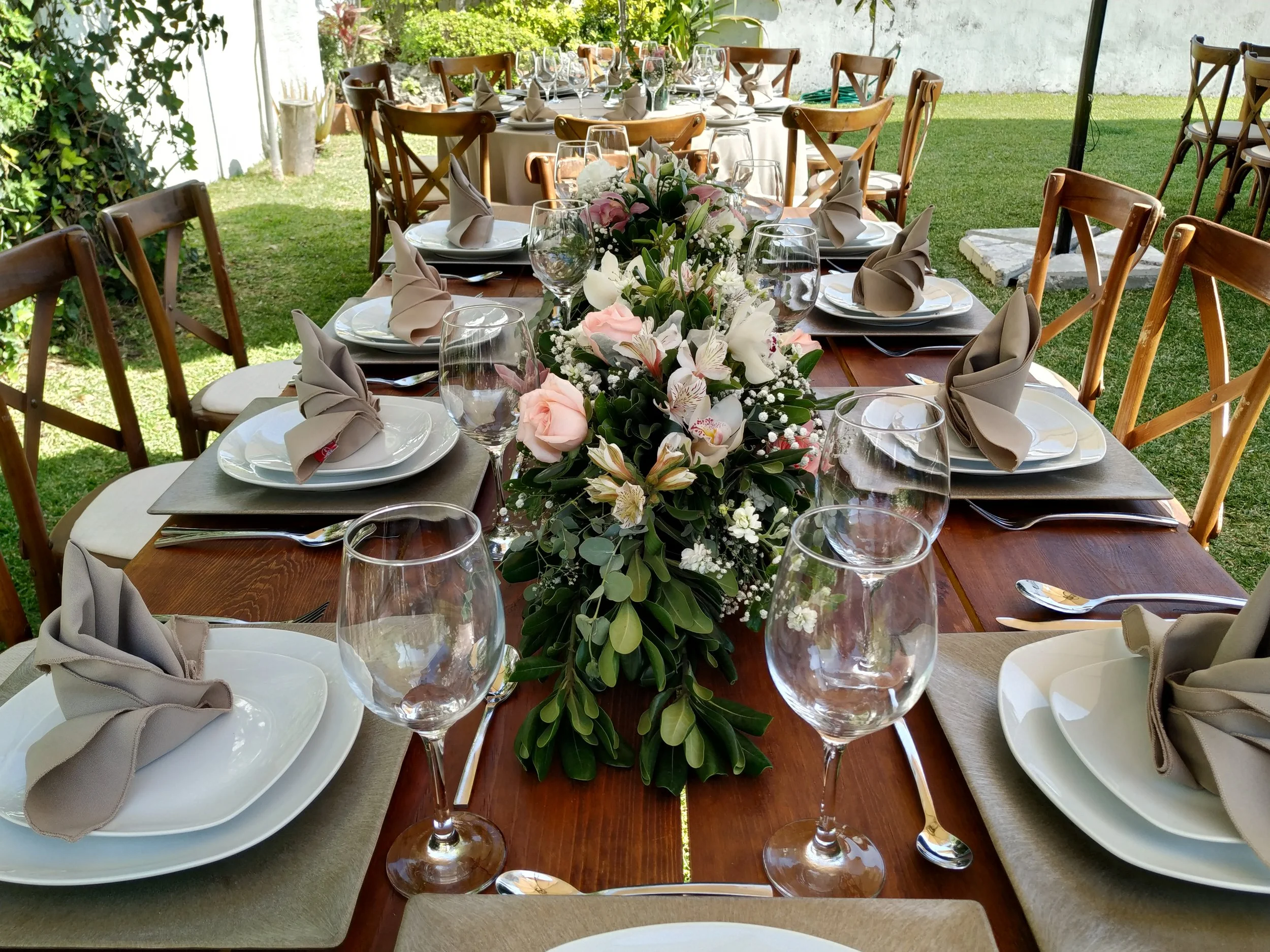 Montaje en boda con mesas de madera y orquídeas en los arreglos florales.