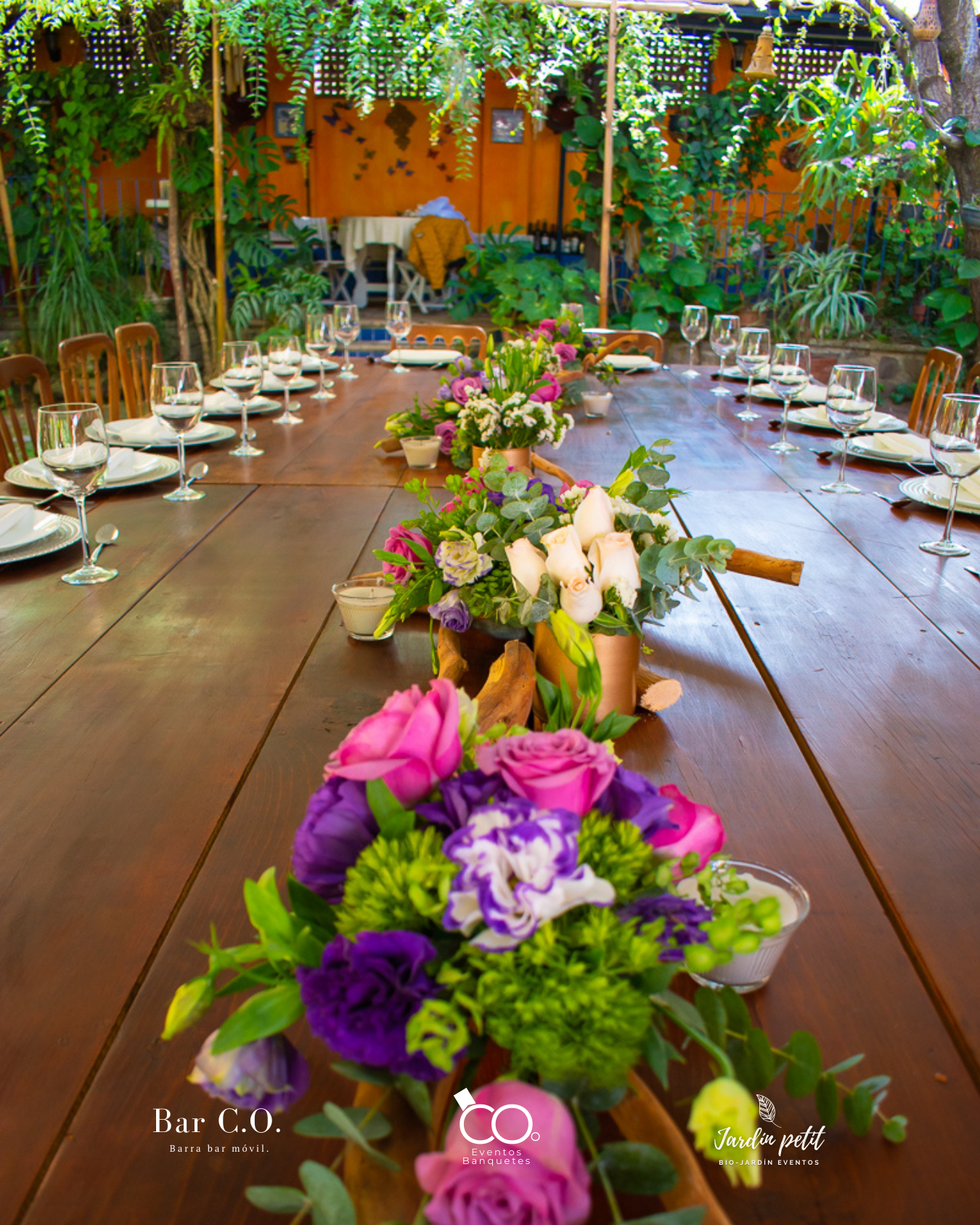 Montaje de mesa larga con centros florales naturales para celebración en jardín.