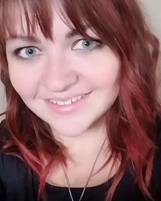 Close-up of Adelia Kindstrand-Clark, LGSW, who has red hair, soft facial features and a welcoming smile.