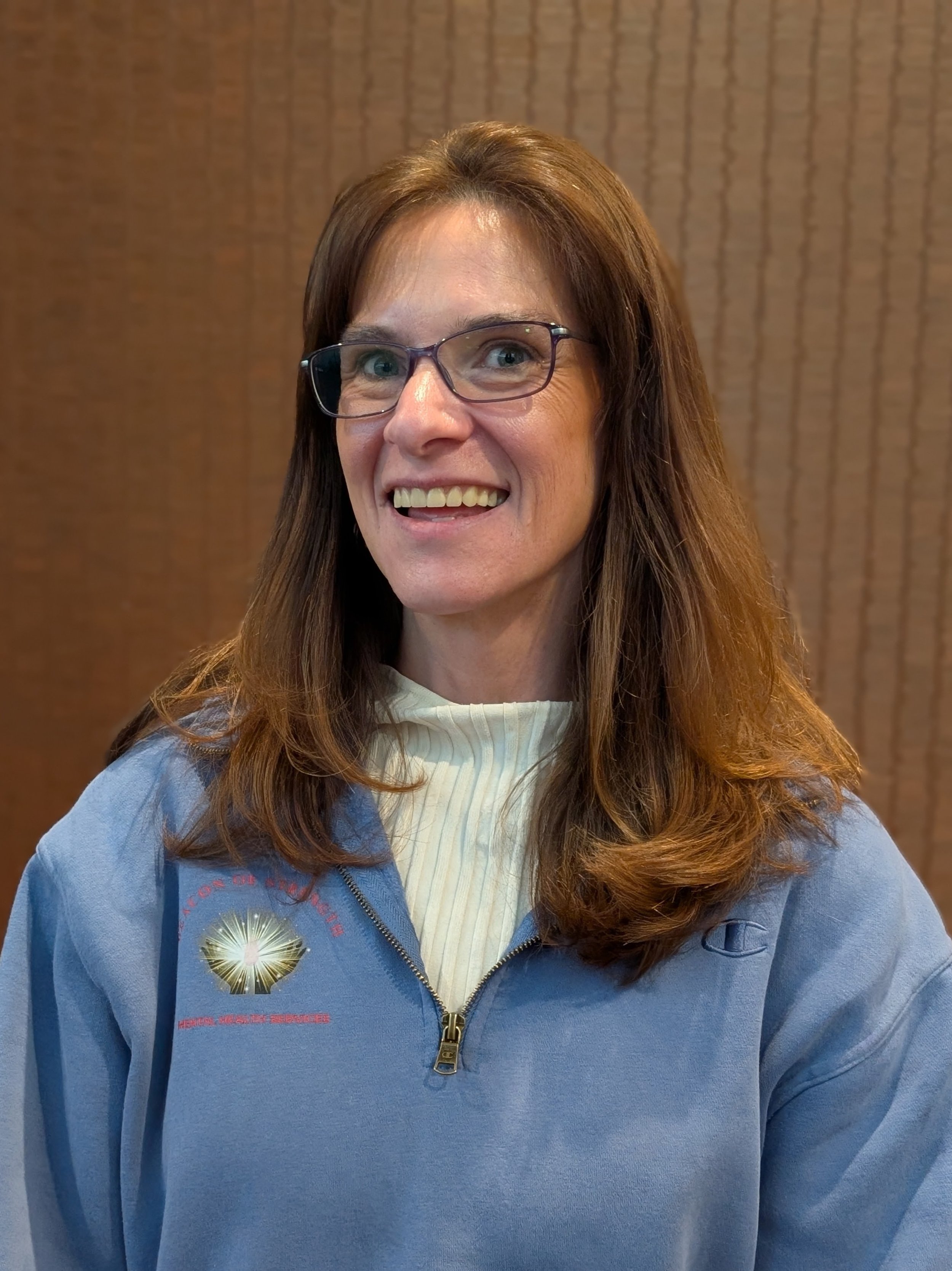 Close-up of Donna Olsen, LICSW and owner of the practice, who has long brown hair, glasses, and a slight smile.