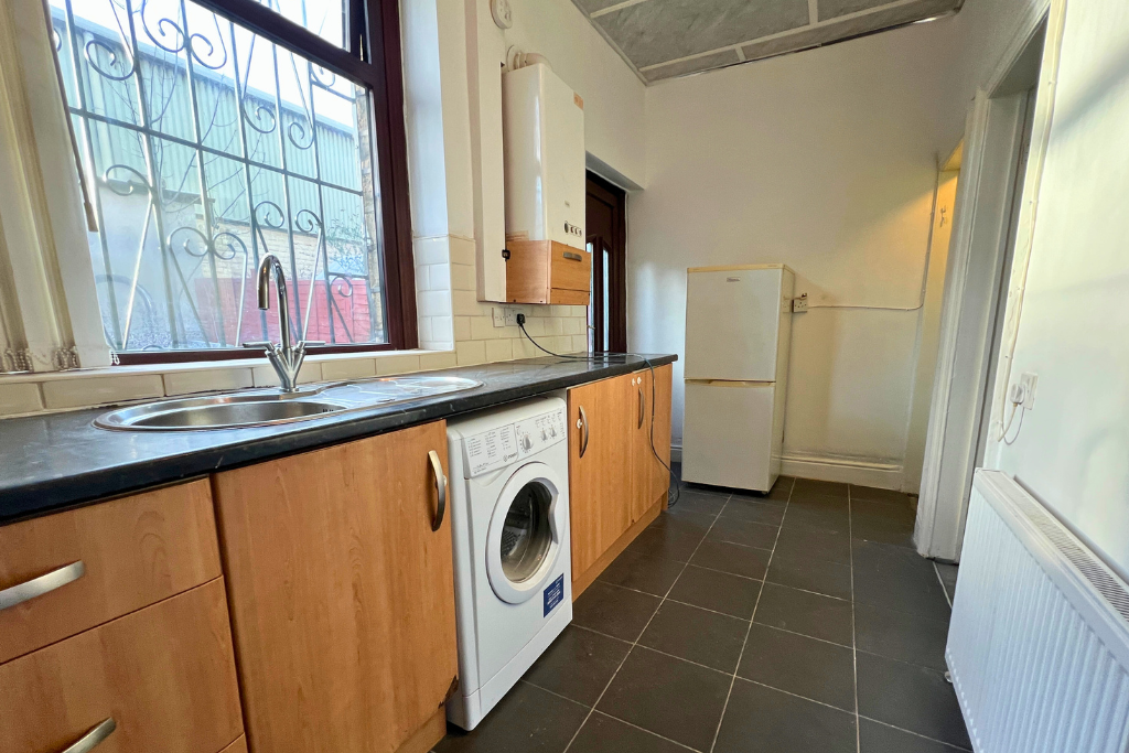 Kitchen with a window, double sink, washing machine, refrigerator, and wooden cabinets.