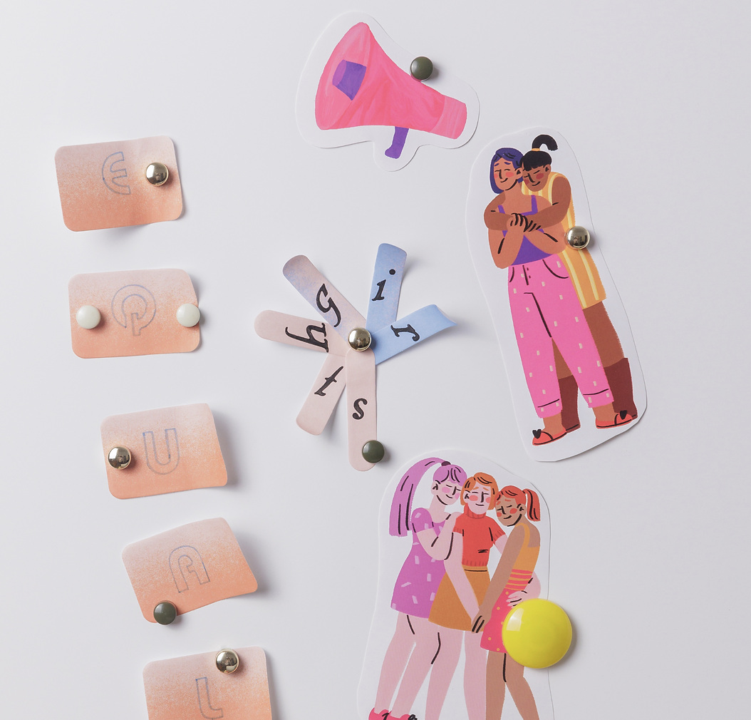 Colorful illustrated stickers of women hugging and talking, a pink megaphone, and paper squares with letters arranged in a circle all pinned on a white surface.