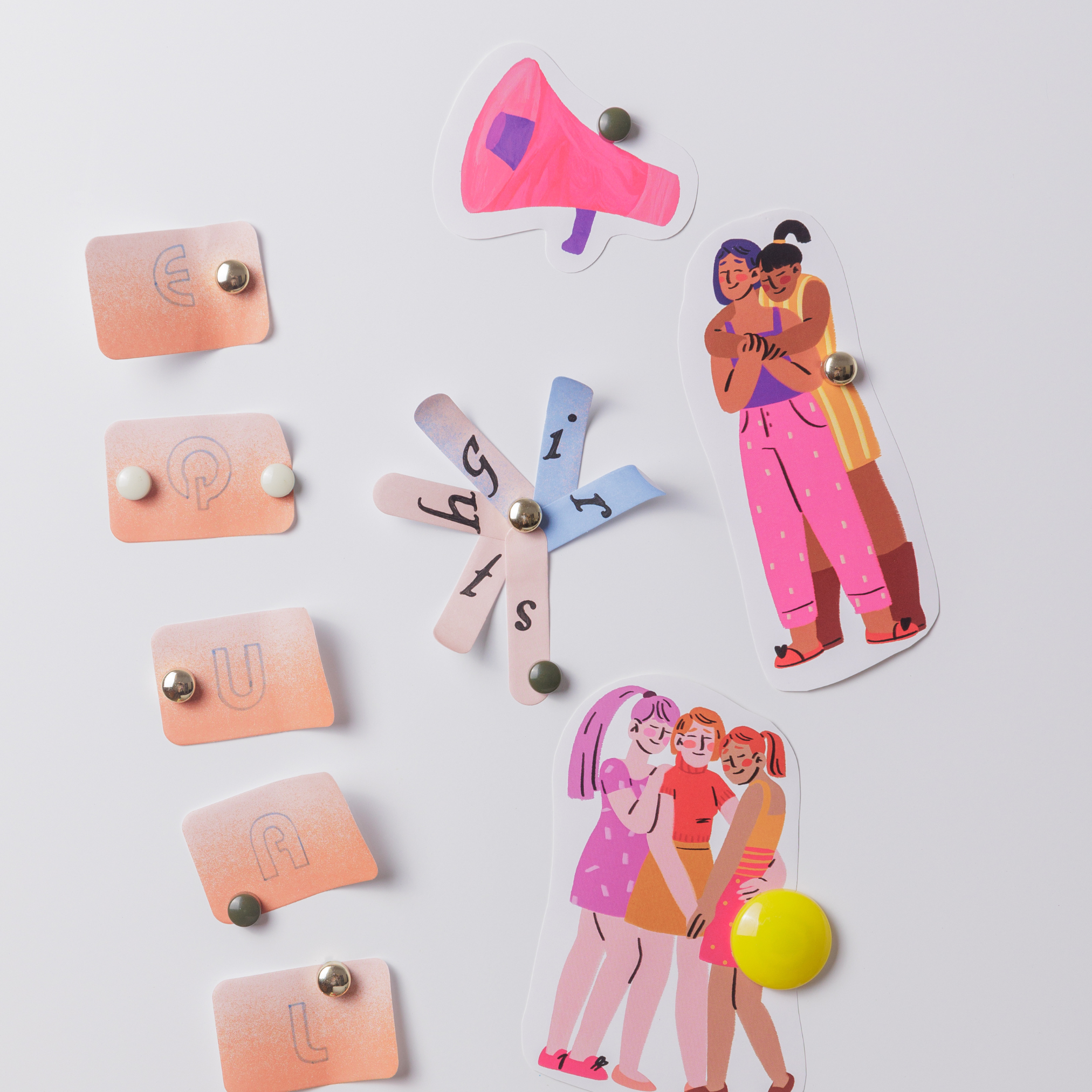 A whiteboard with magnetic letters, cartoon cutouts of three women, a pink megaphone, and a yellow magnet.