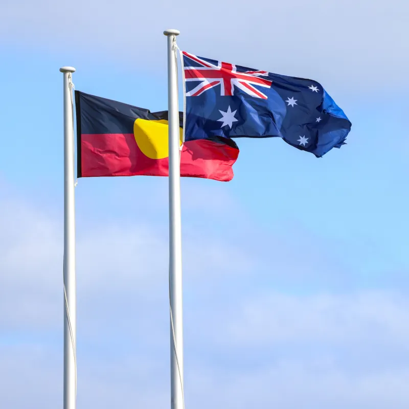 Australian and Aboriginal flags flying against a blue sky.