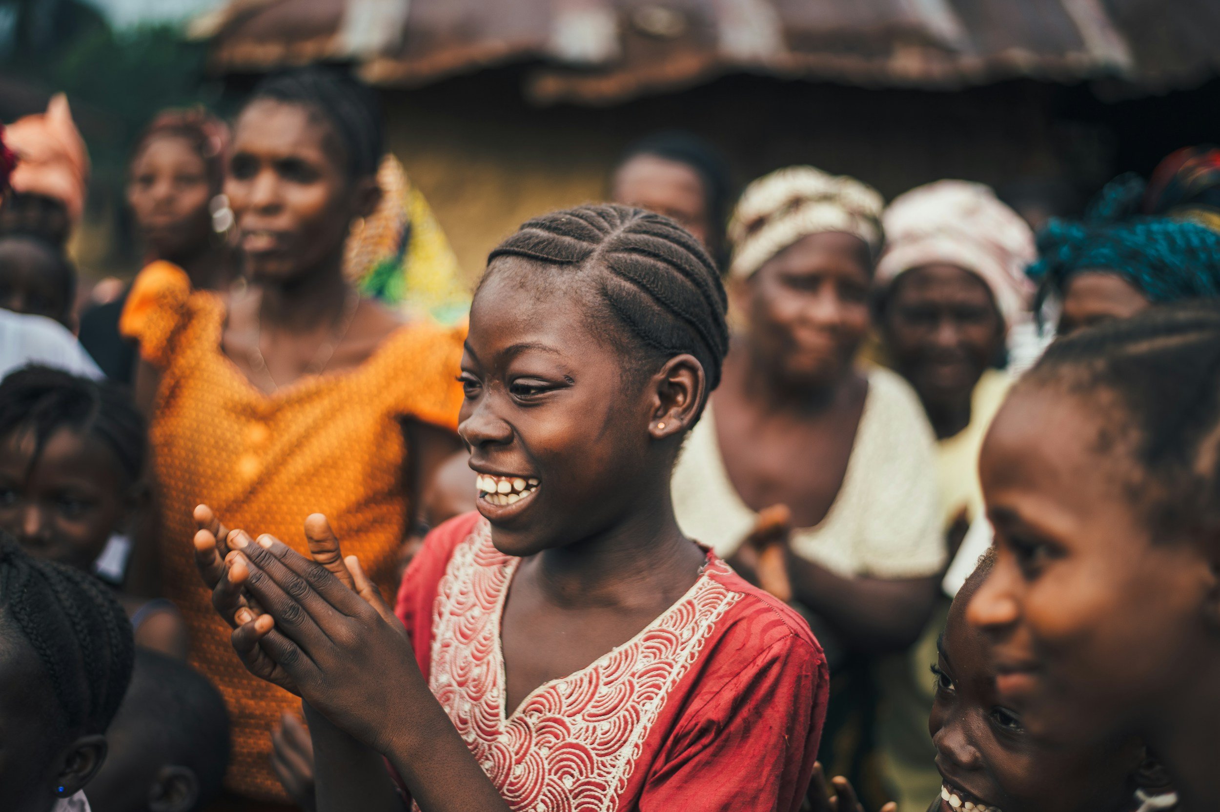 A group of women in colorful clothing, smiling and engaging in a moment of joy, outdoors.
