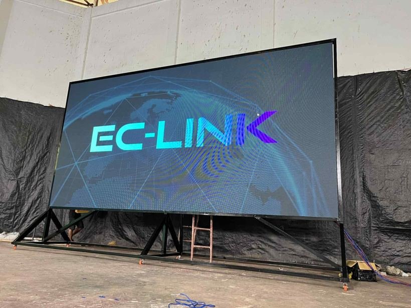 Large digital screen displaying the text 'EC-LINK' with a globe graphic in the background, set up in an industrial or warehouse setting.