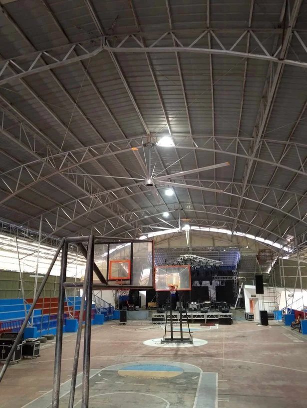Indoor basketball court with stage, lighting, and seating area.