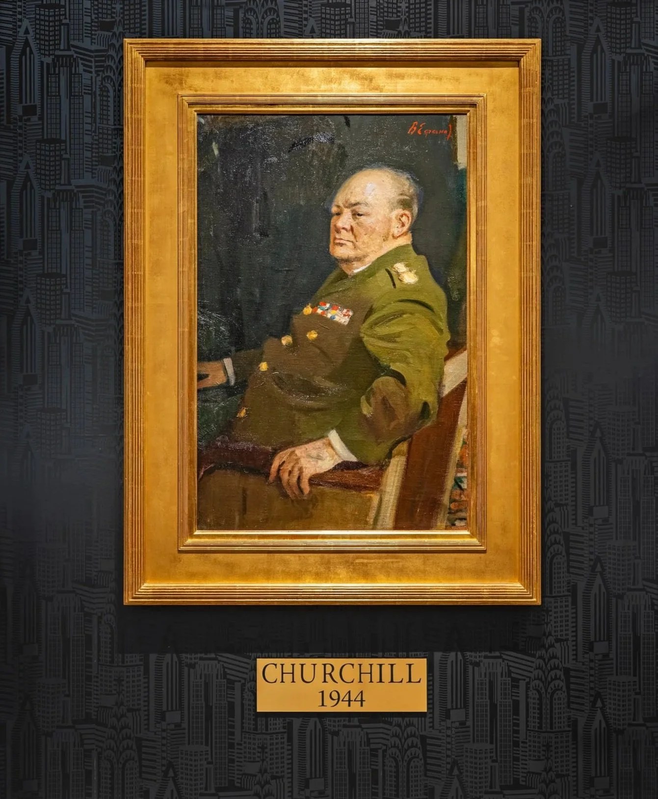 A portrait of Winston Churchill in 1944, featuring him seated in a military uniform with medals, in a gold frame against a dark background with a cityscape pattern.