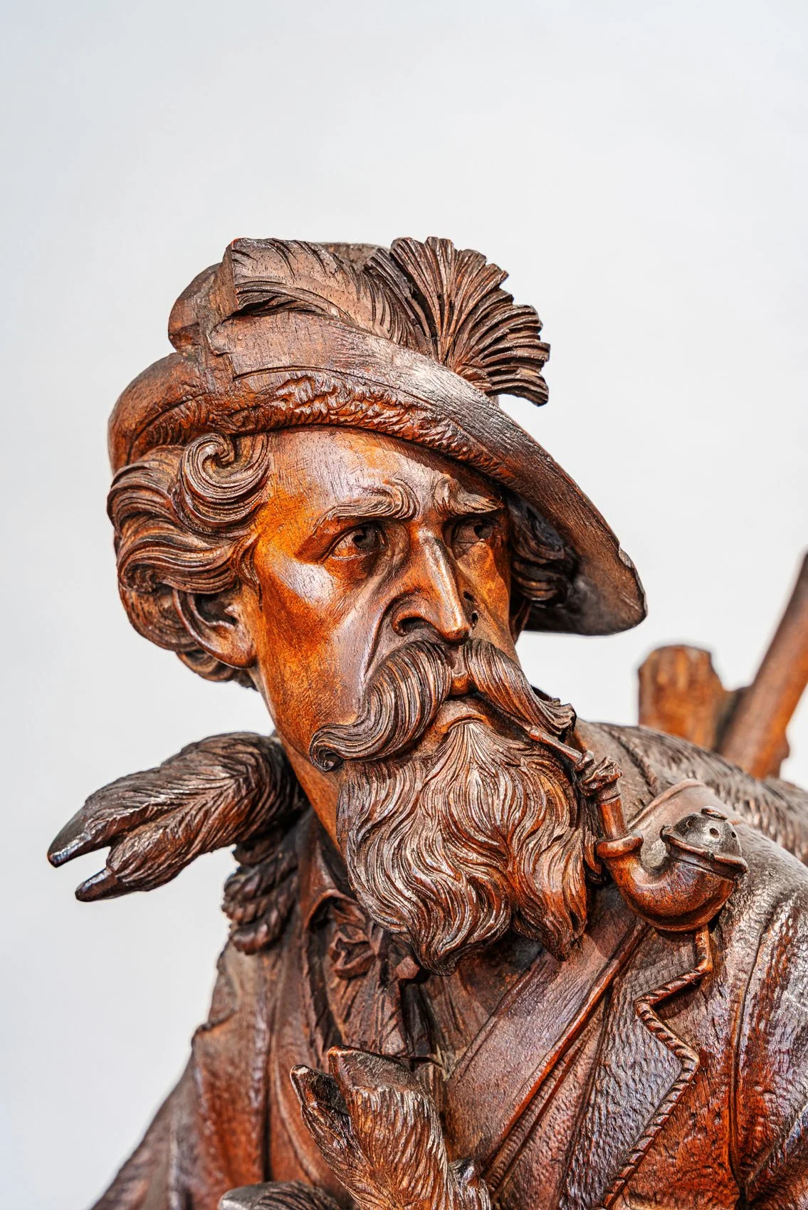 Detail of hunter's face, feathered hat and pipe, signed J. Huggler Swiss Black Forest clock, Brienz