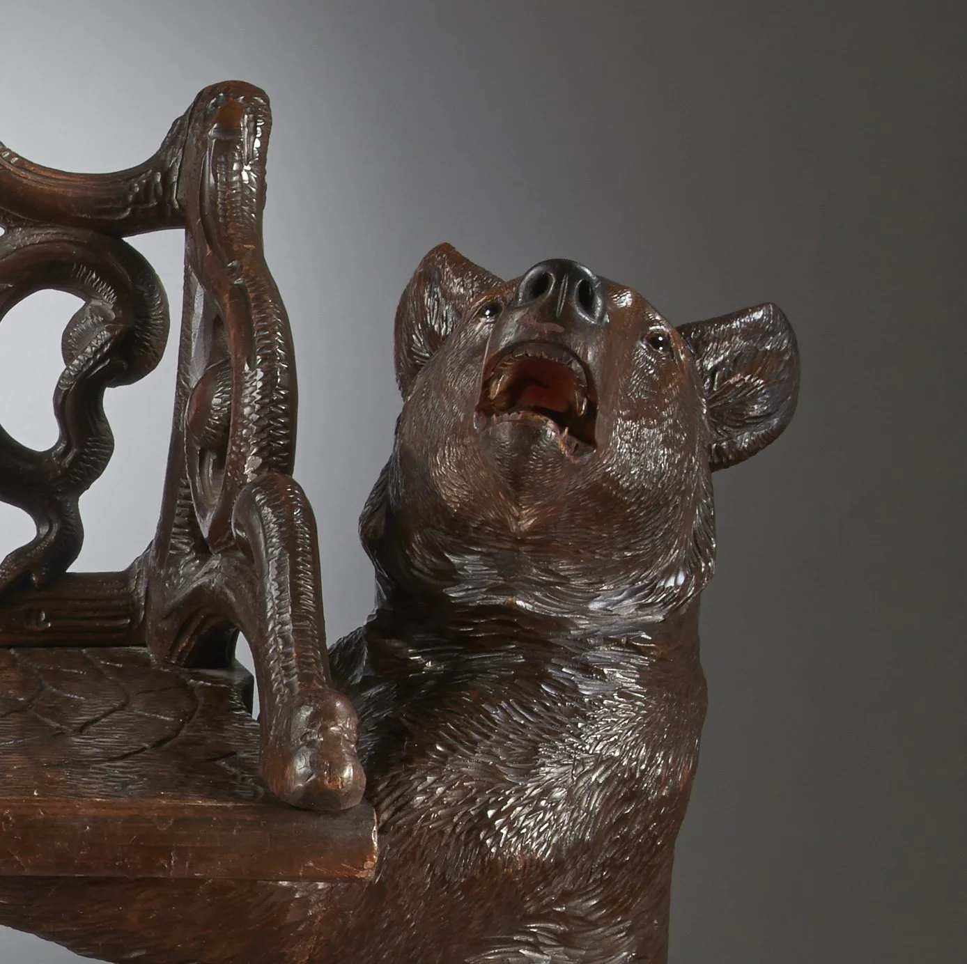 Head of a carved standing bear with open mouth and glass eyes, end support of a Swiss Black Forest bear bench, circa 1870
