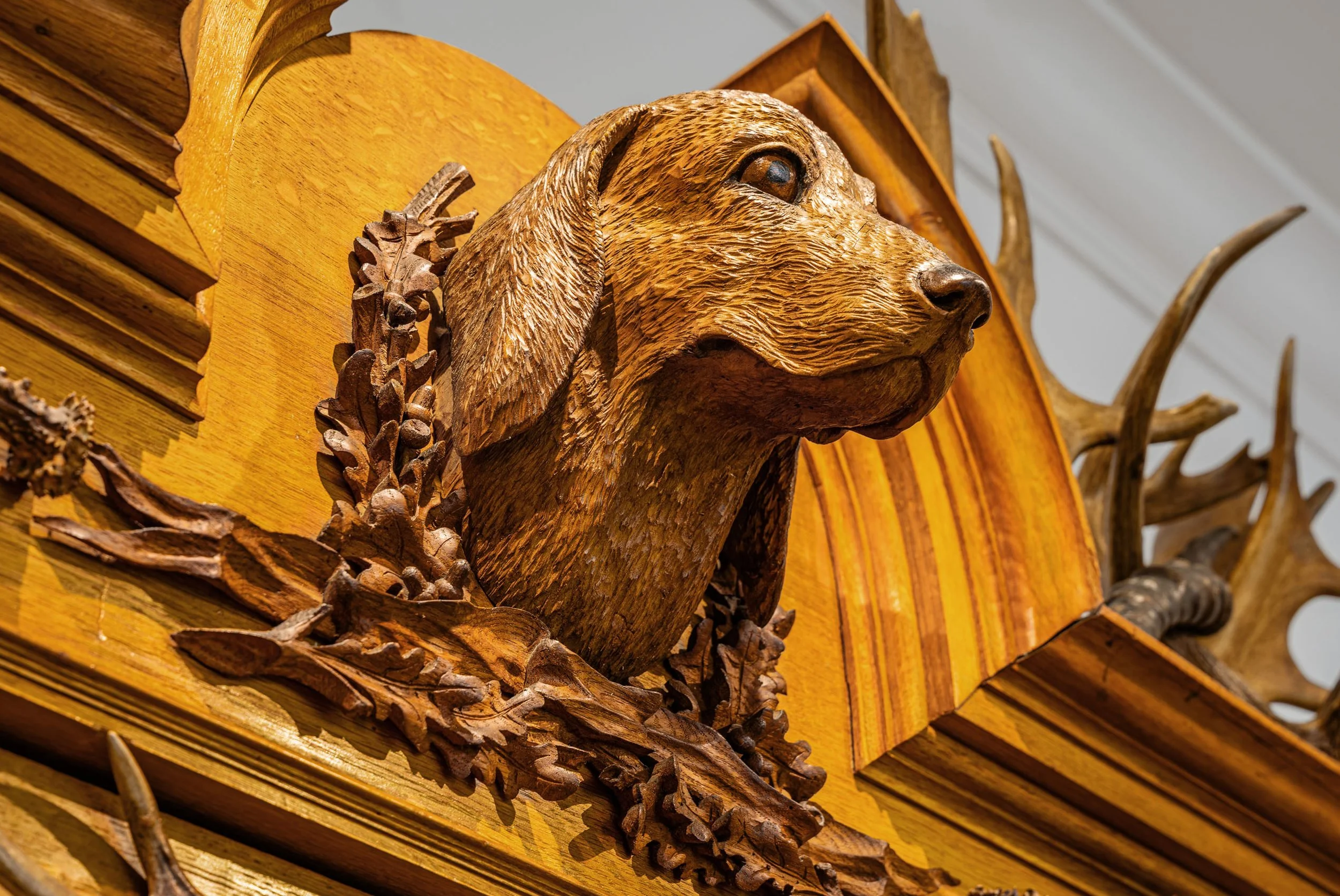 Carved hound's head with glass eyes surmounting arched crest, Black Forest hunting cabinet Jagdschrank, late 19th century