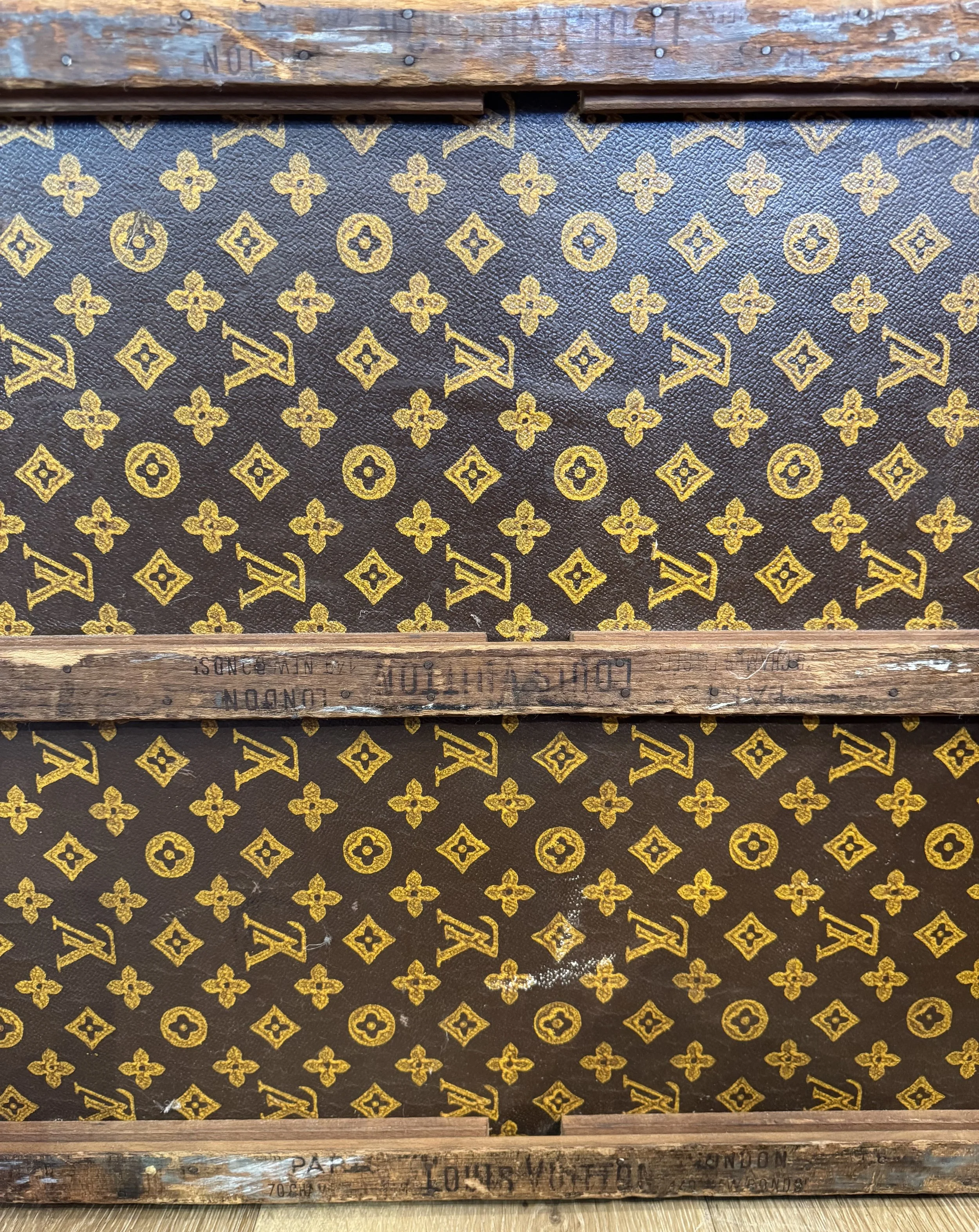 Underside of a Louis Vuitton Monogram trunk showing darkened unbleached canvas and LV stamp on base timber slat — Daniels Antiques