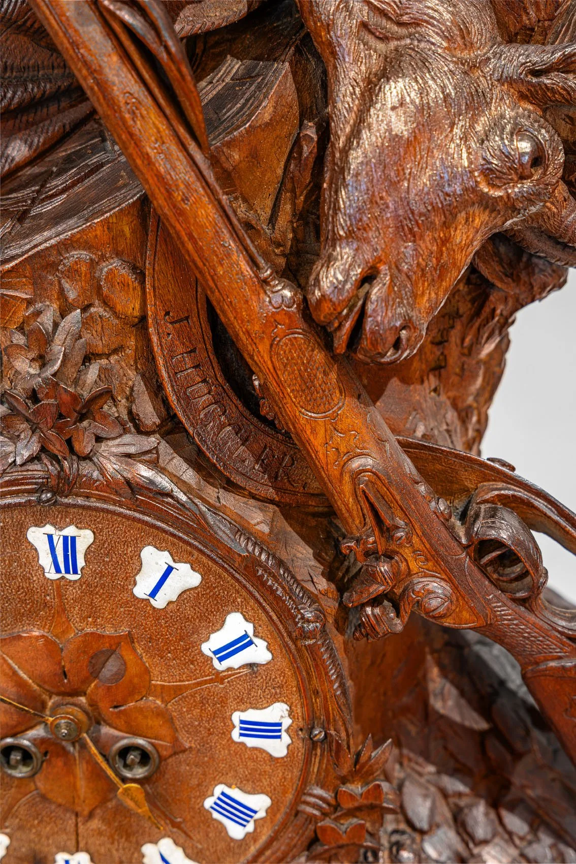 J. Huggler signature on rifle stock and enamel clock dial detail, Swiss Black Forest hunter clock, Brienz