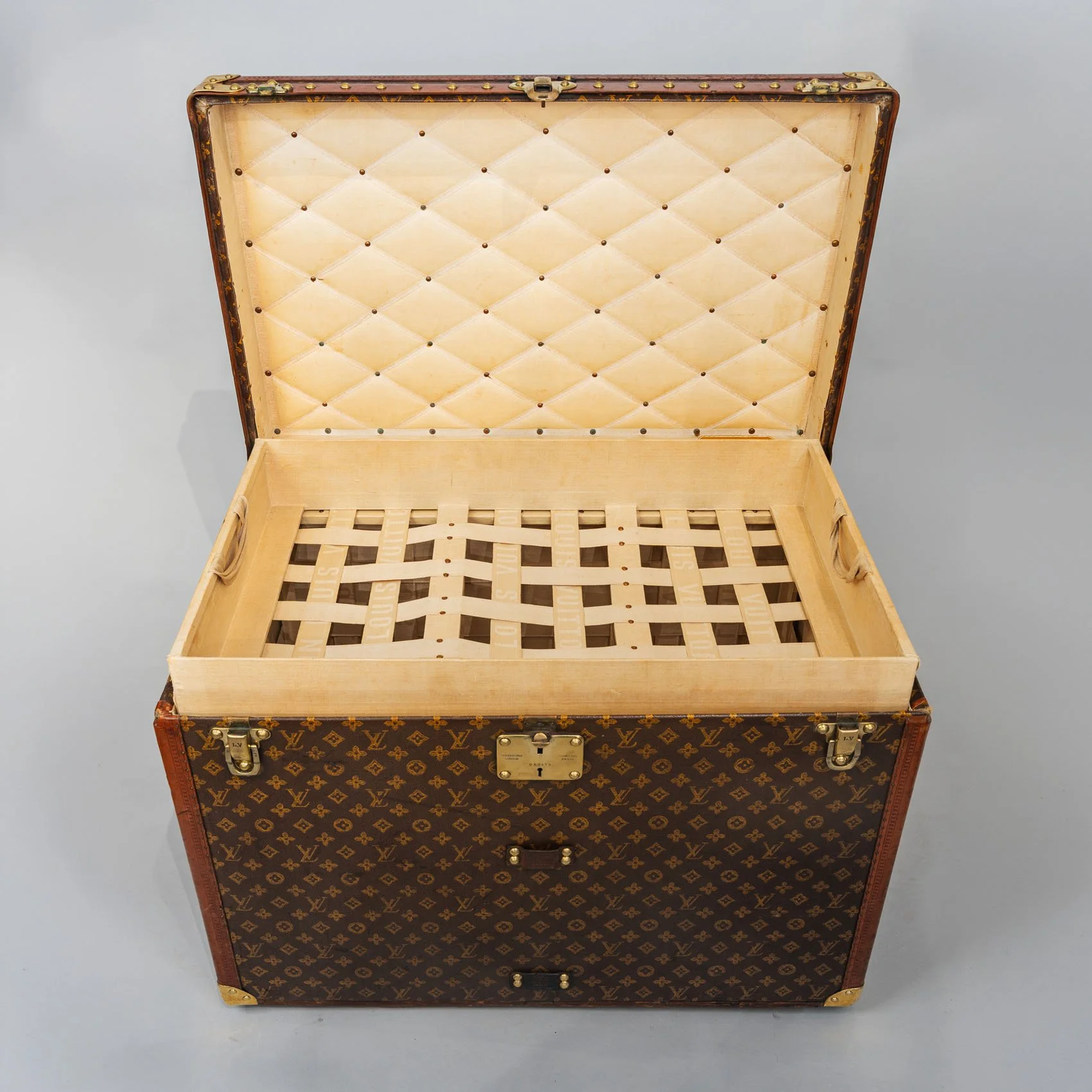Interior of Louis Vuitton half steamer trunk showing original woven linen tray and quilted lid lining