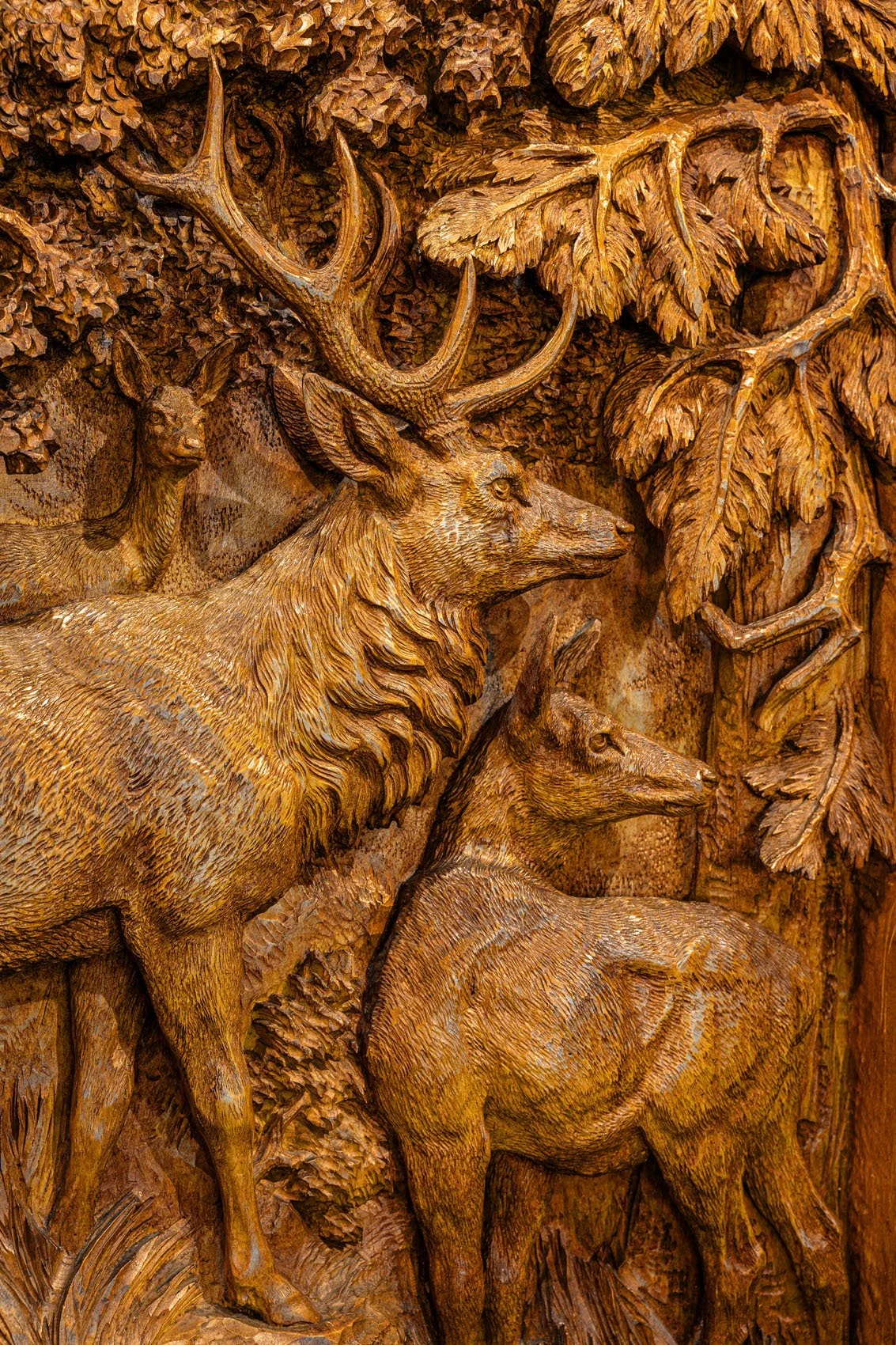 Deep-relief carved panel detail of stag, hind and fawn in forest, Black Forest hunting cabinet, late 19th century