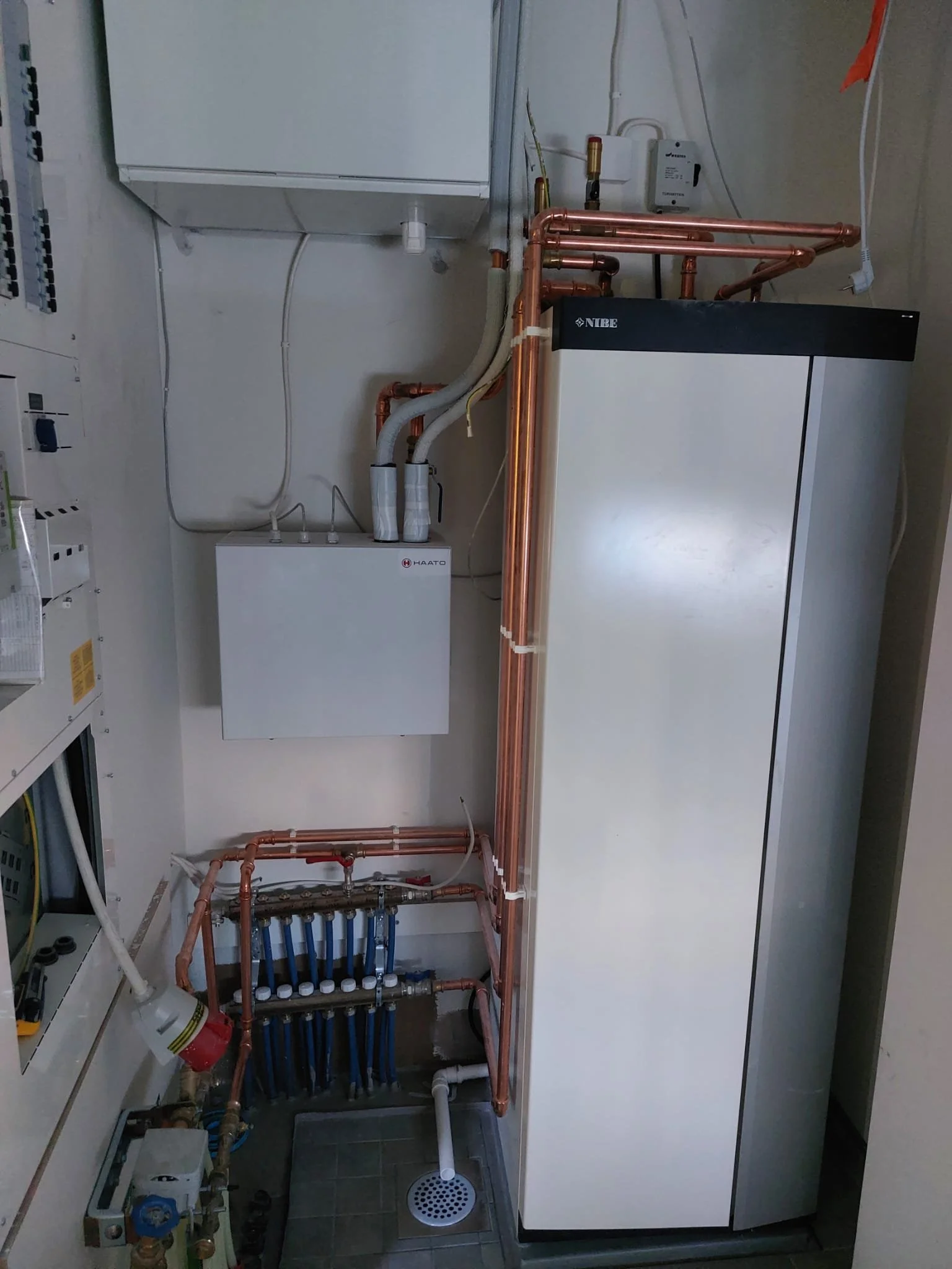 Lämmitysjärjestelmä huoneessa, jossa on putkia ja laitteita.