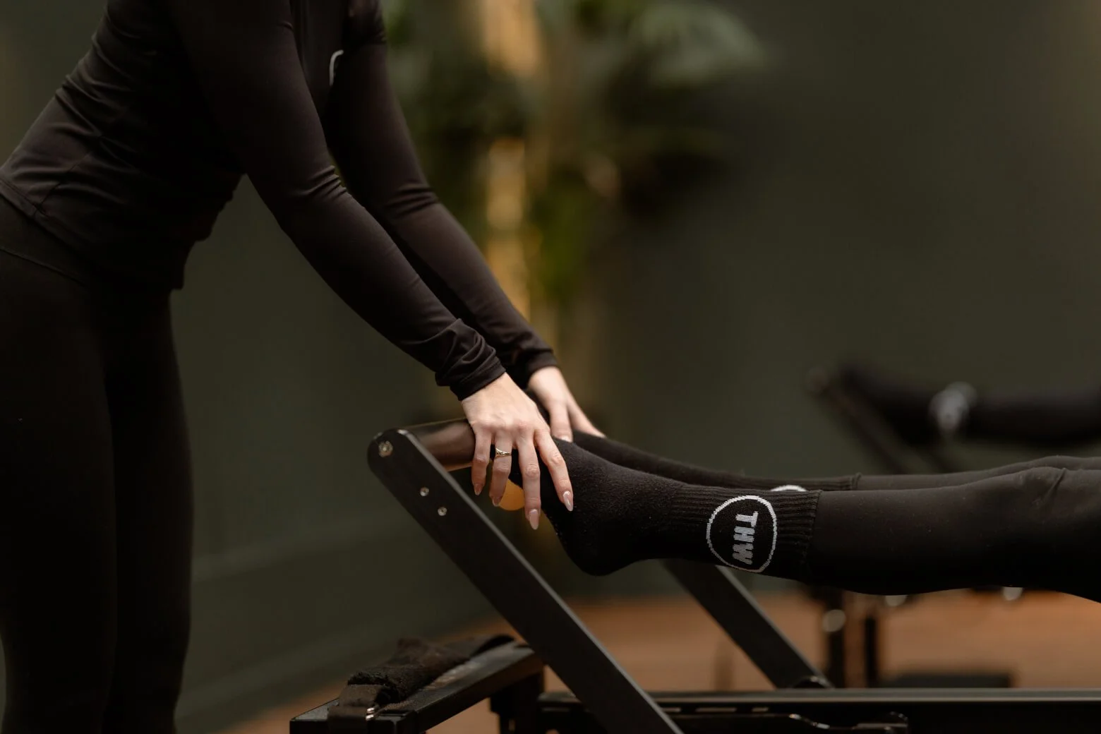 THW Reformer Pilates instructor supporting a client