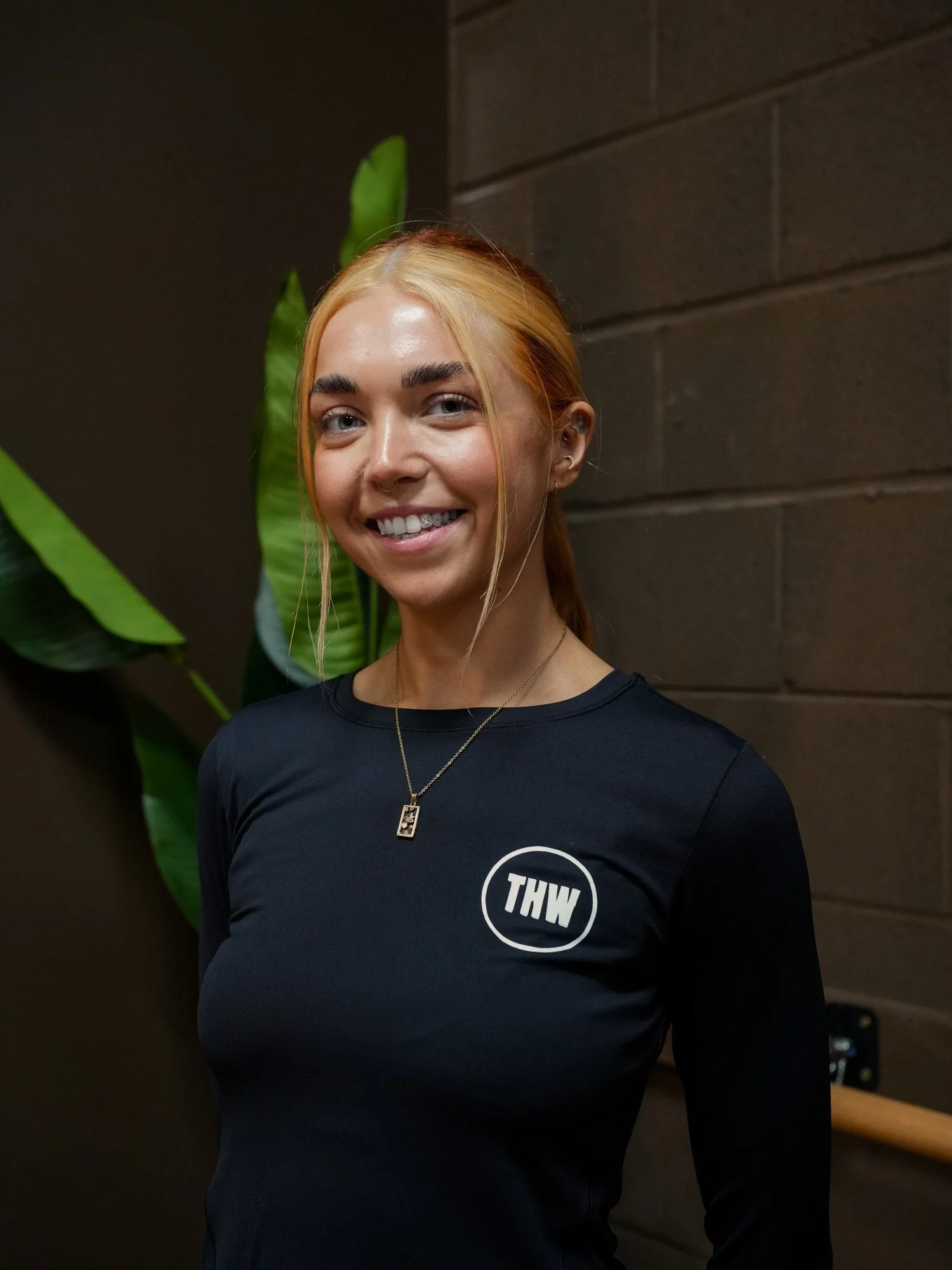 THW yoga teacher smiling in a black branded top inside the Tradeston studio.