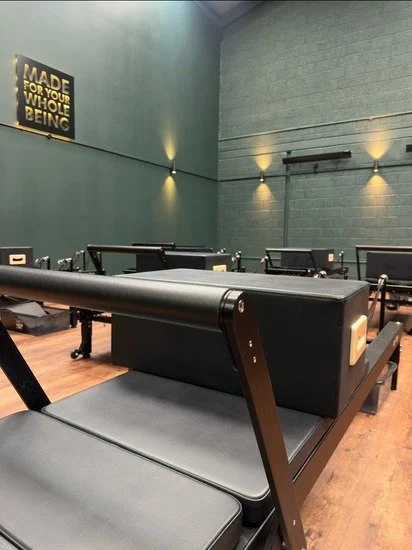 Close up image of a reformer Pilates machine in a large room in a warehouse.