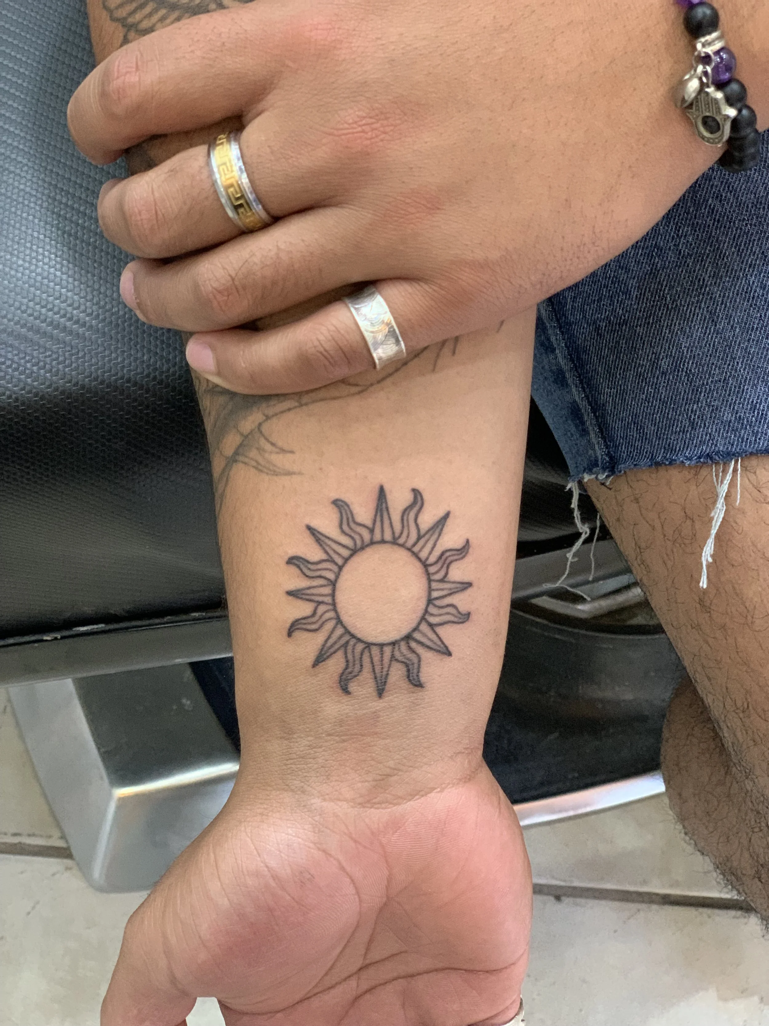 sun tattoo fine line on wrist by kidd in cabo best tattoo artist
