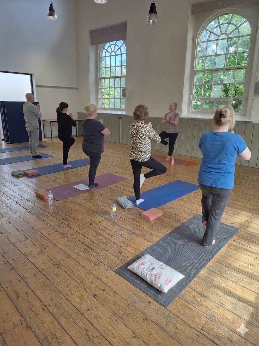 Yoga class practicing tree pose on mats in a bright studio with arched windows