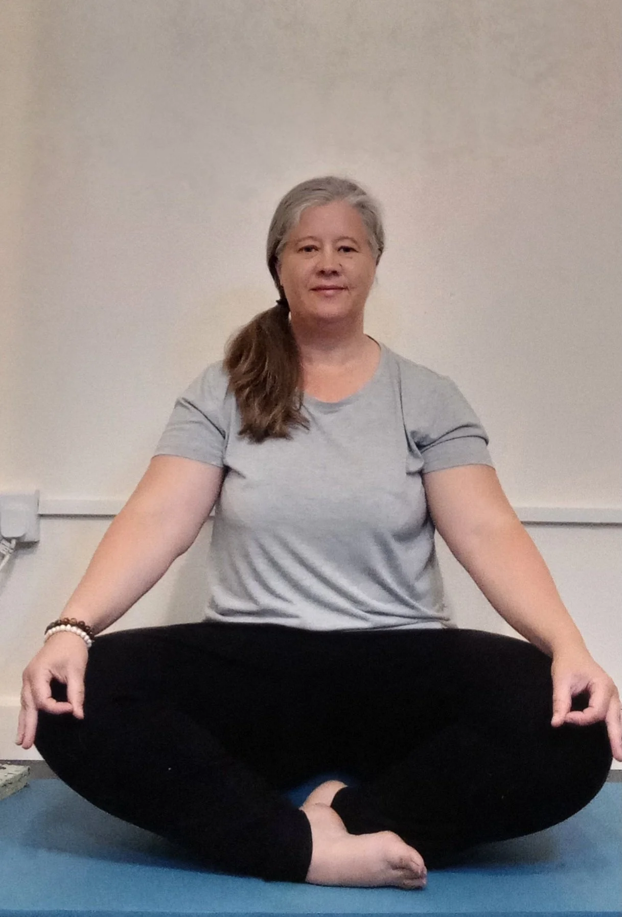 Person sitting cross-legged on a mat in a meditative pose.