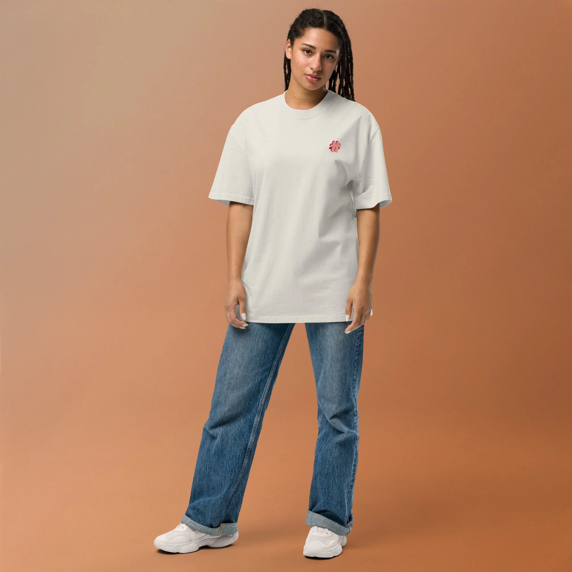 Person in sunglasses wearing an oversized t-shirt in cream colour that has a small #TeamTranslator logo on the left side of the chest.