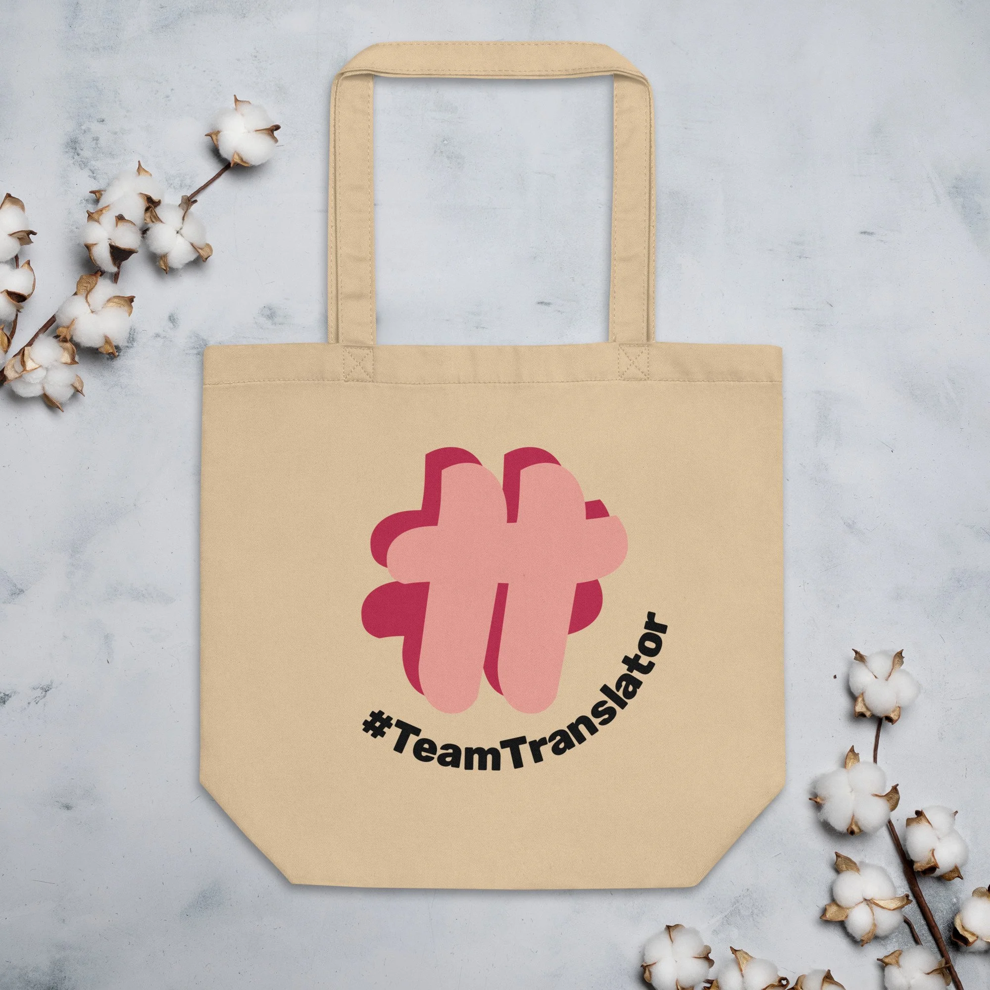 The oyster-coloured (dark creamy coloured) tote bag with a large printed #TT logo amongst cotton flowers.