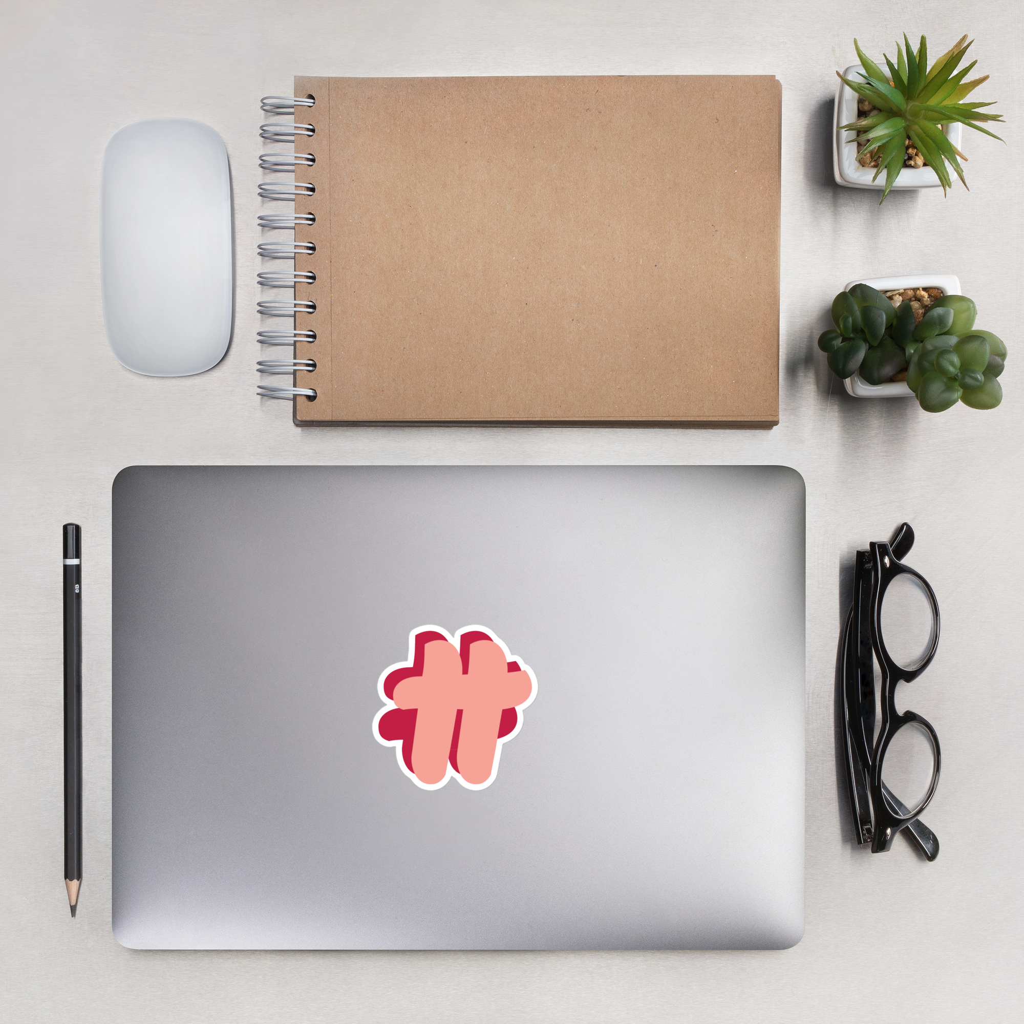 #TT logo without text as a sticker on a laptop's top. It's on a table together with a notebook, succulents and glasses.