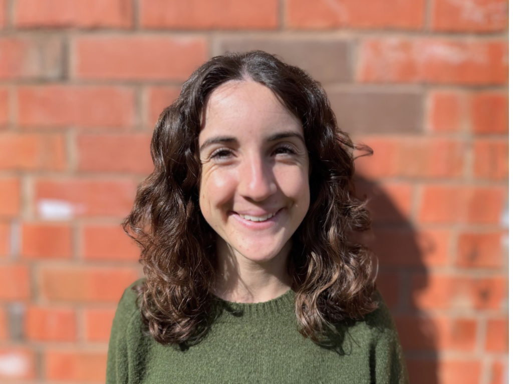 Profile picture of Emeline Cizeron, with long curly brown hair, wearing a green jumper.