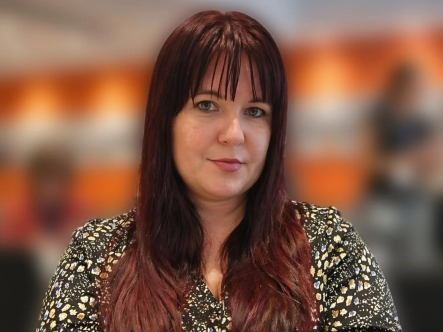 Profile Picture of Andrea T. Egeresi, with long dark red hair, wearing a black-and-white patterned top.