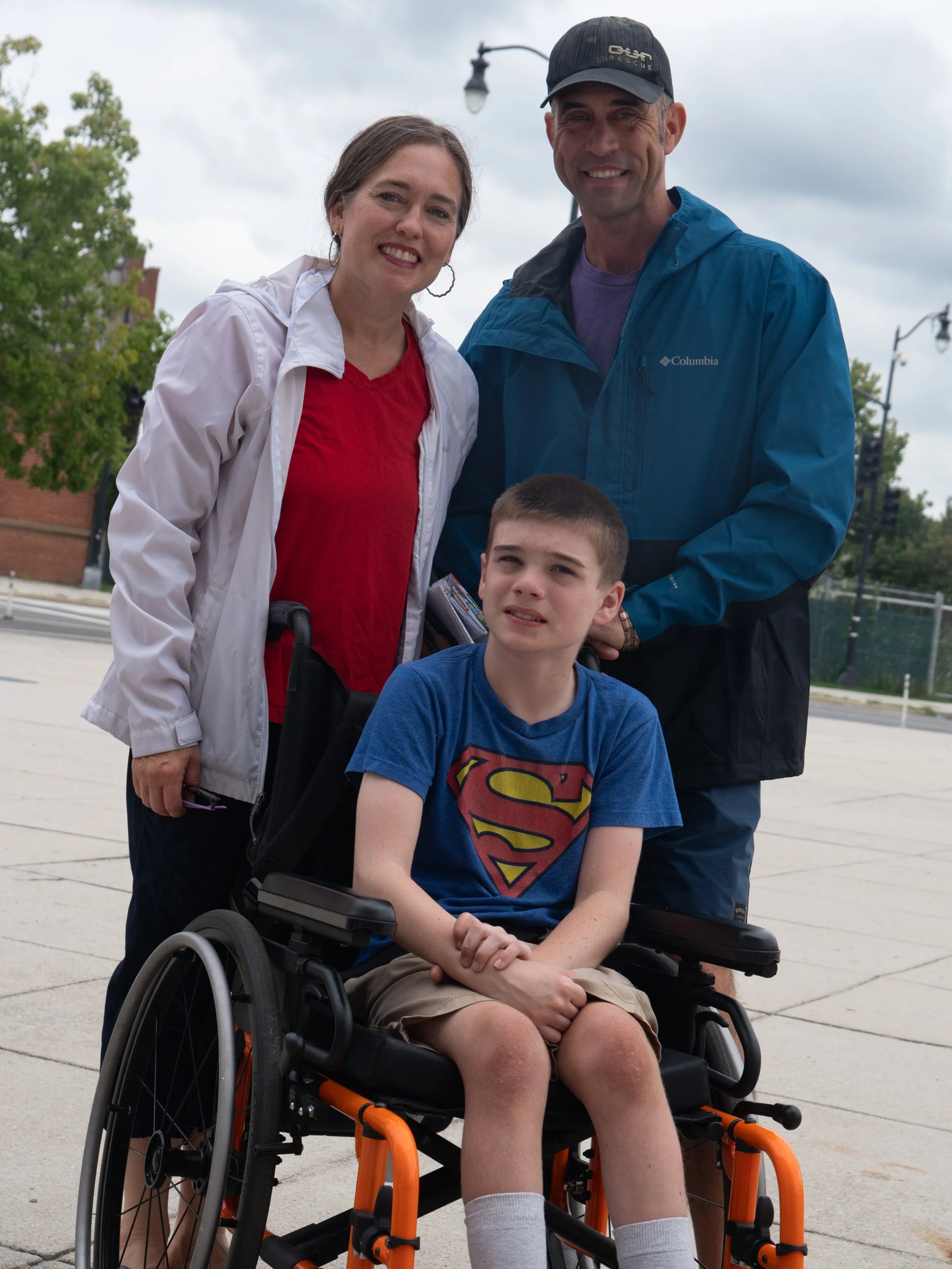 Young wheelchair user poses with two family members outside Nationals Park