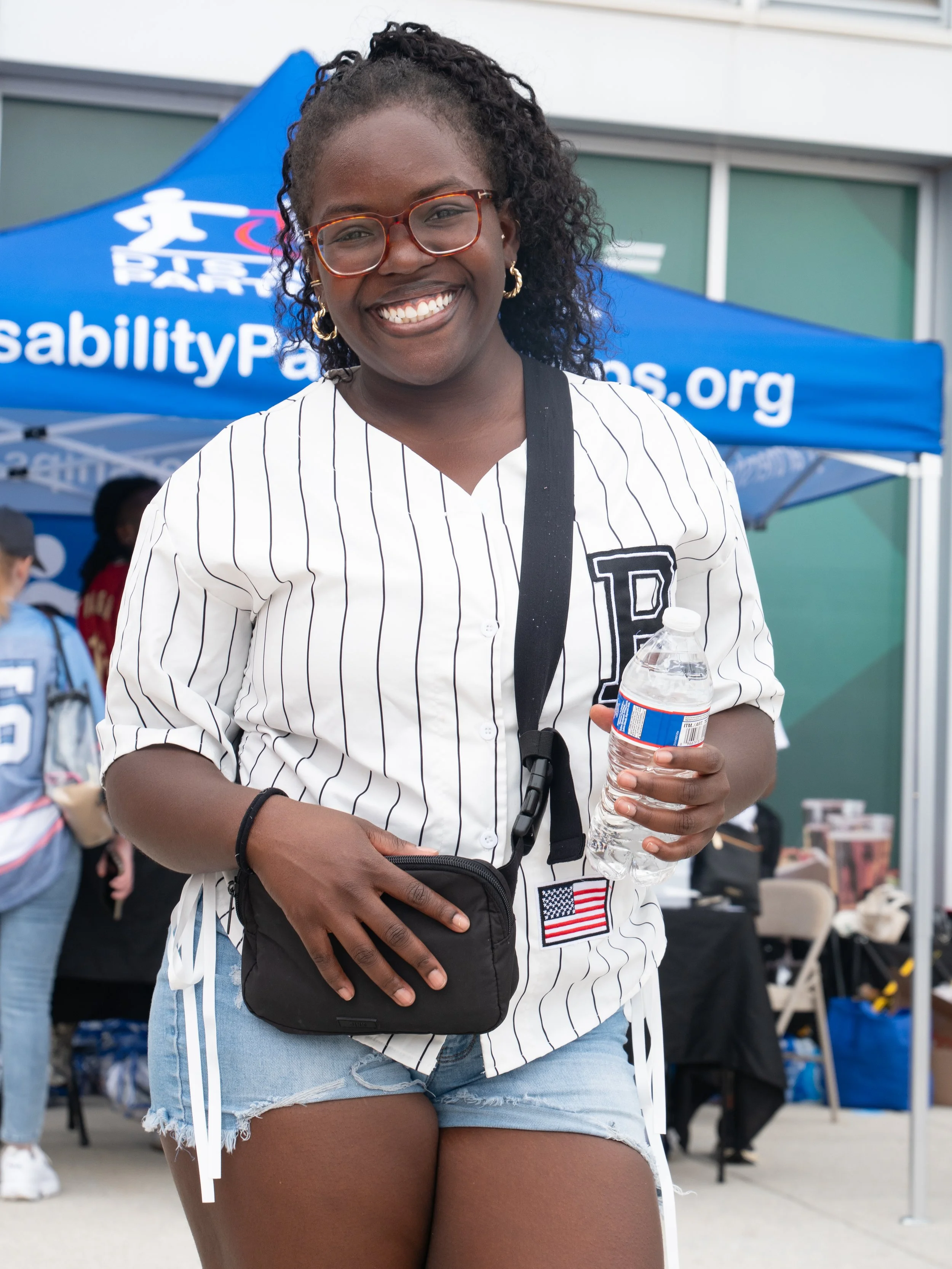 Play Without Limits attendee smiles in front of the Disability Partnerships event tent