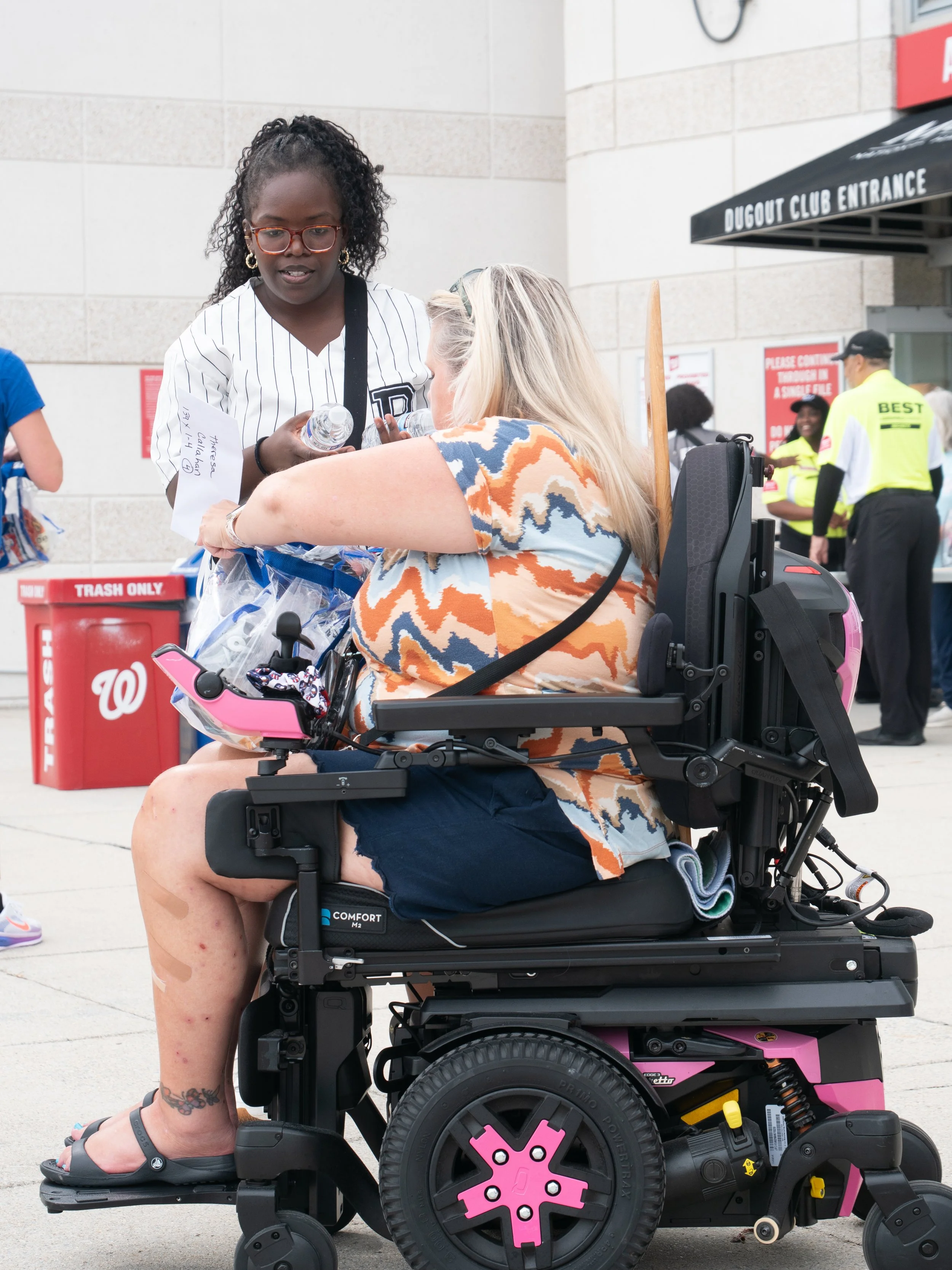 Volunteer assists a wheelchair user with event materials outside Nationals Park