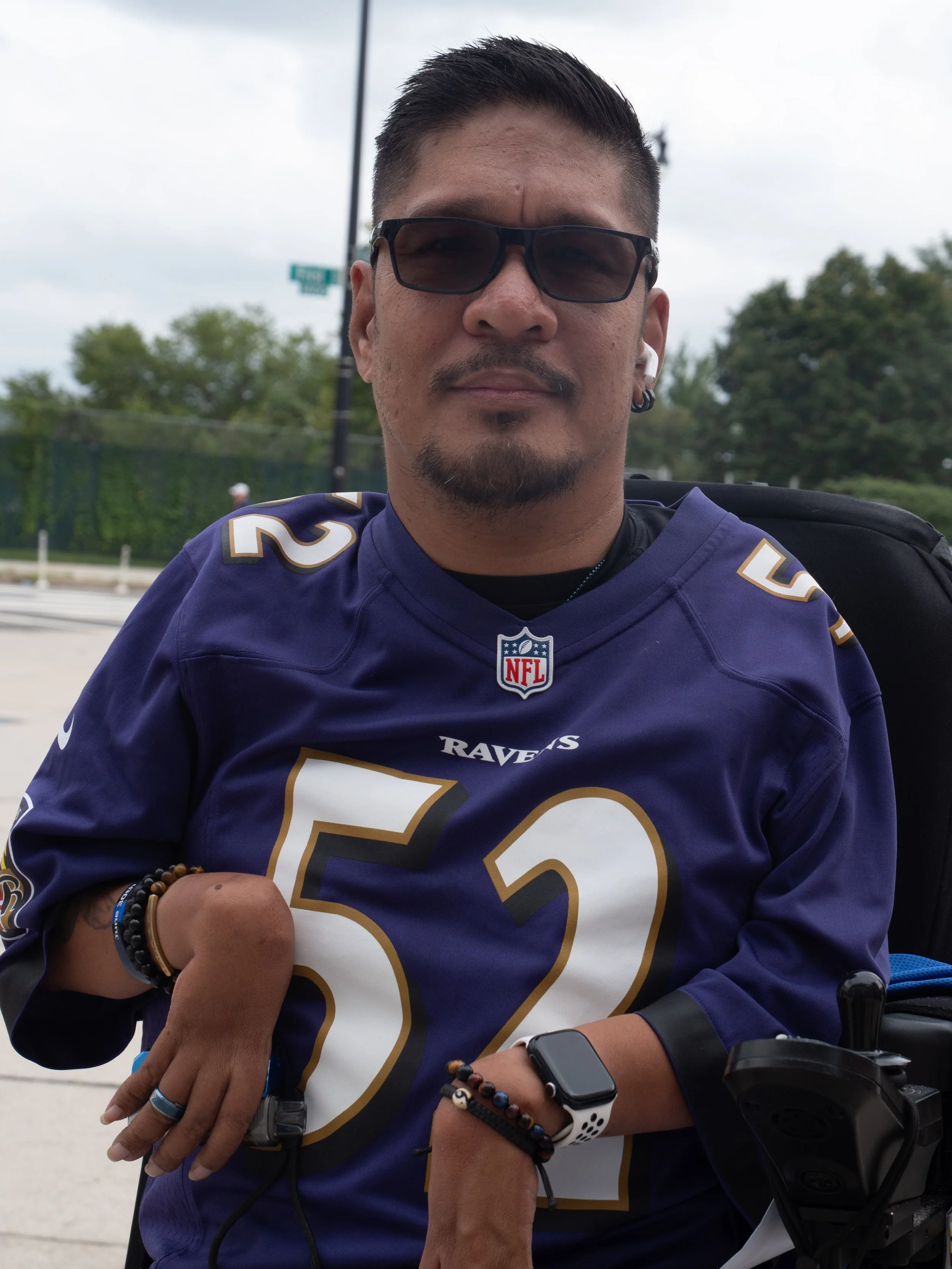 Wheelchair user wearing a Baltimore Ravens jersey poses outside Nationals Park