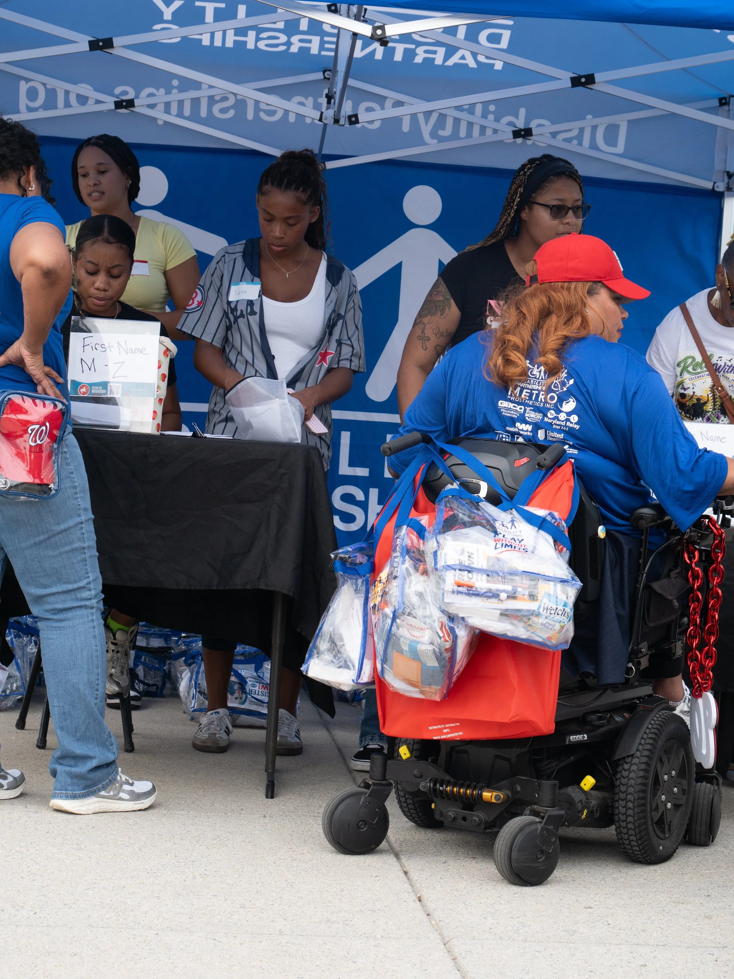 Volunteers distribute Play Without Limits materials at the Disability Partnerships welcome tent