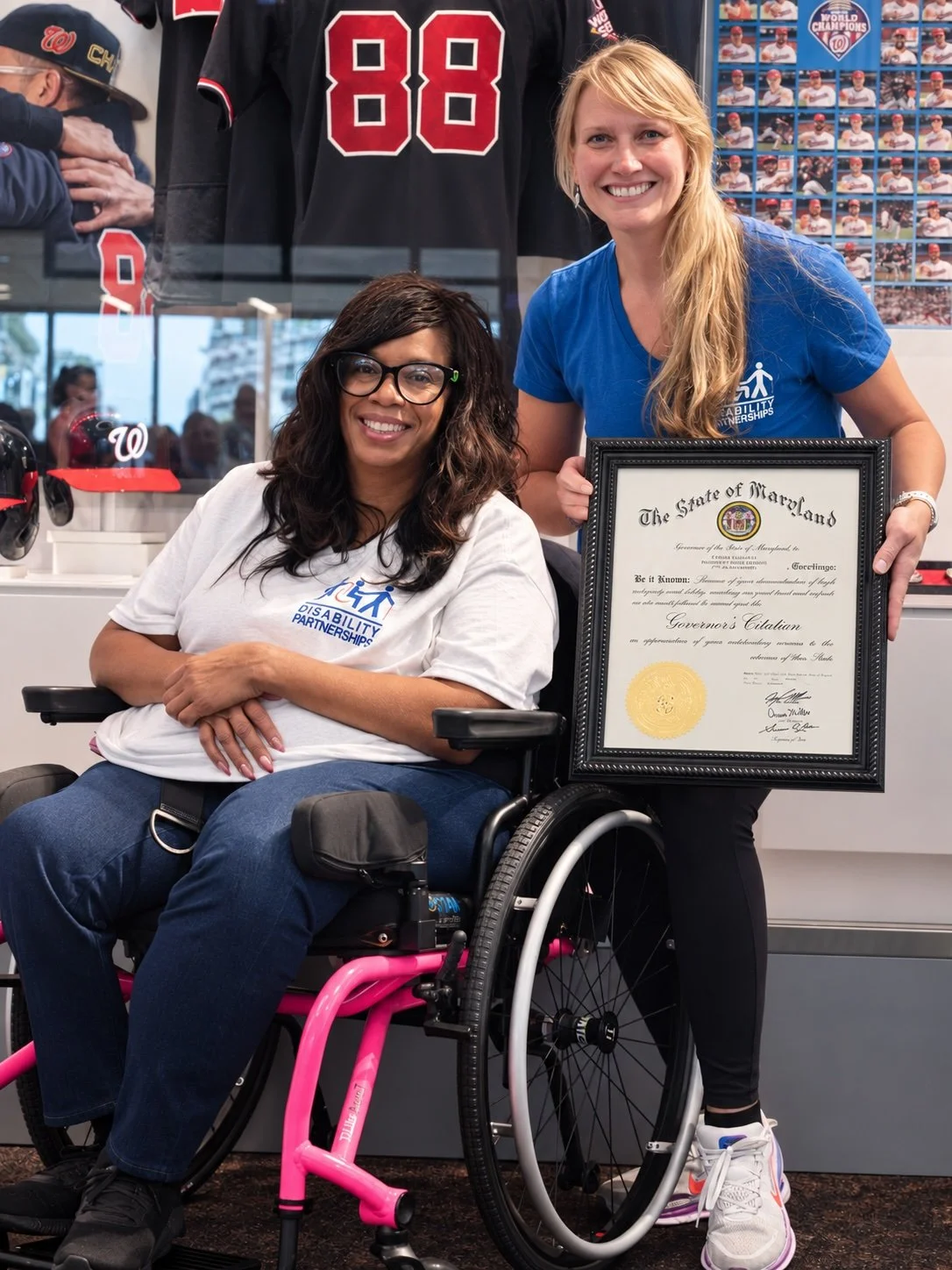 Two Disability Partnerships team members pose with a framed Maryland Governor’s Citation