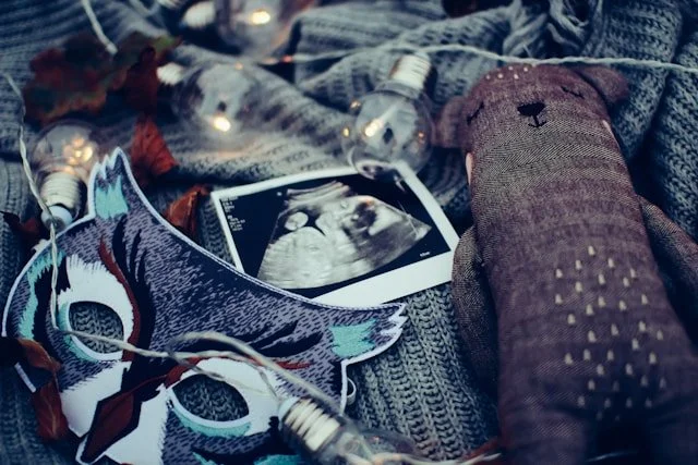 Virtual birth doula support: 12 week scan photo and a teddy bear laid out on a soft blanket