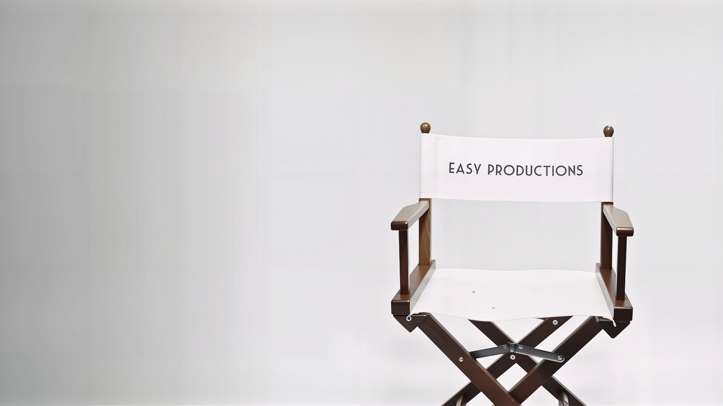 Klassischer Regiestuhl aus Holz mit weißem Stoffbezug. Auf der Rückenlehne steht in schwarzen Großbuchstaben der Firmenname "EASY PRODUCTIONS". Das Bild dient als Symbol für das Set und die Arbeit der Filmproduktionsfirma.