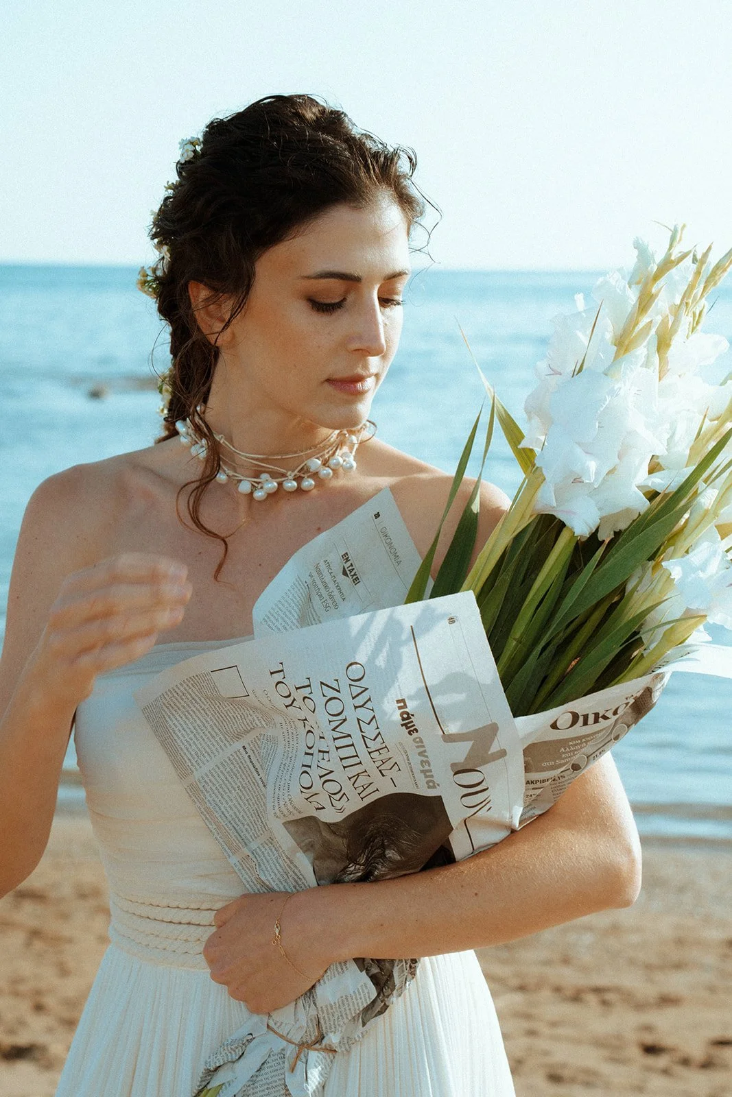 bride with white bouquet in newspaper on the beach