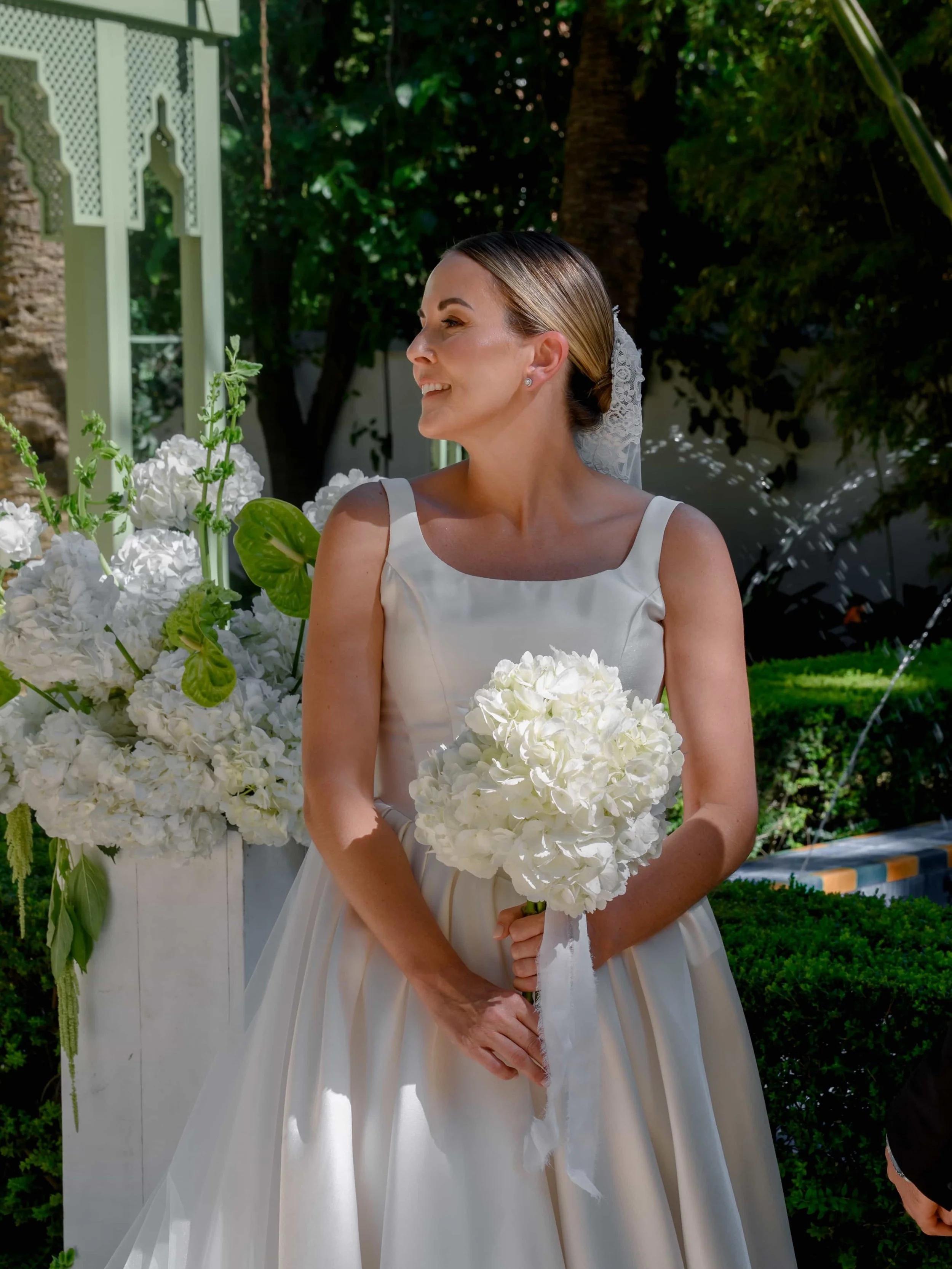 Bride holding her bouquet with white and green backdrop during ceremony 
