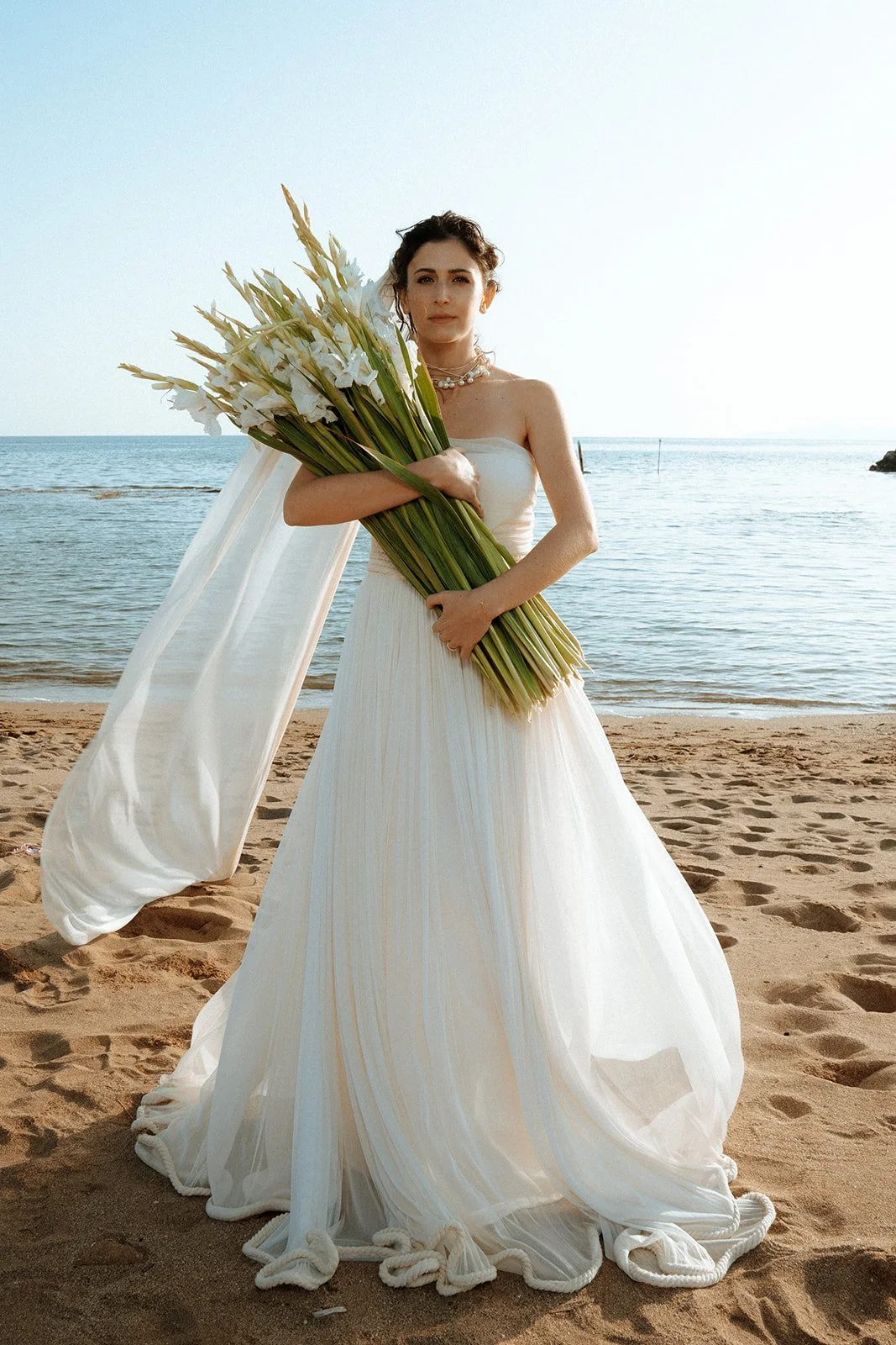 bride on the beach with white bouquet 