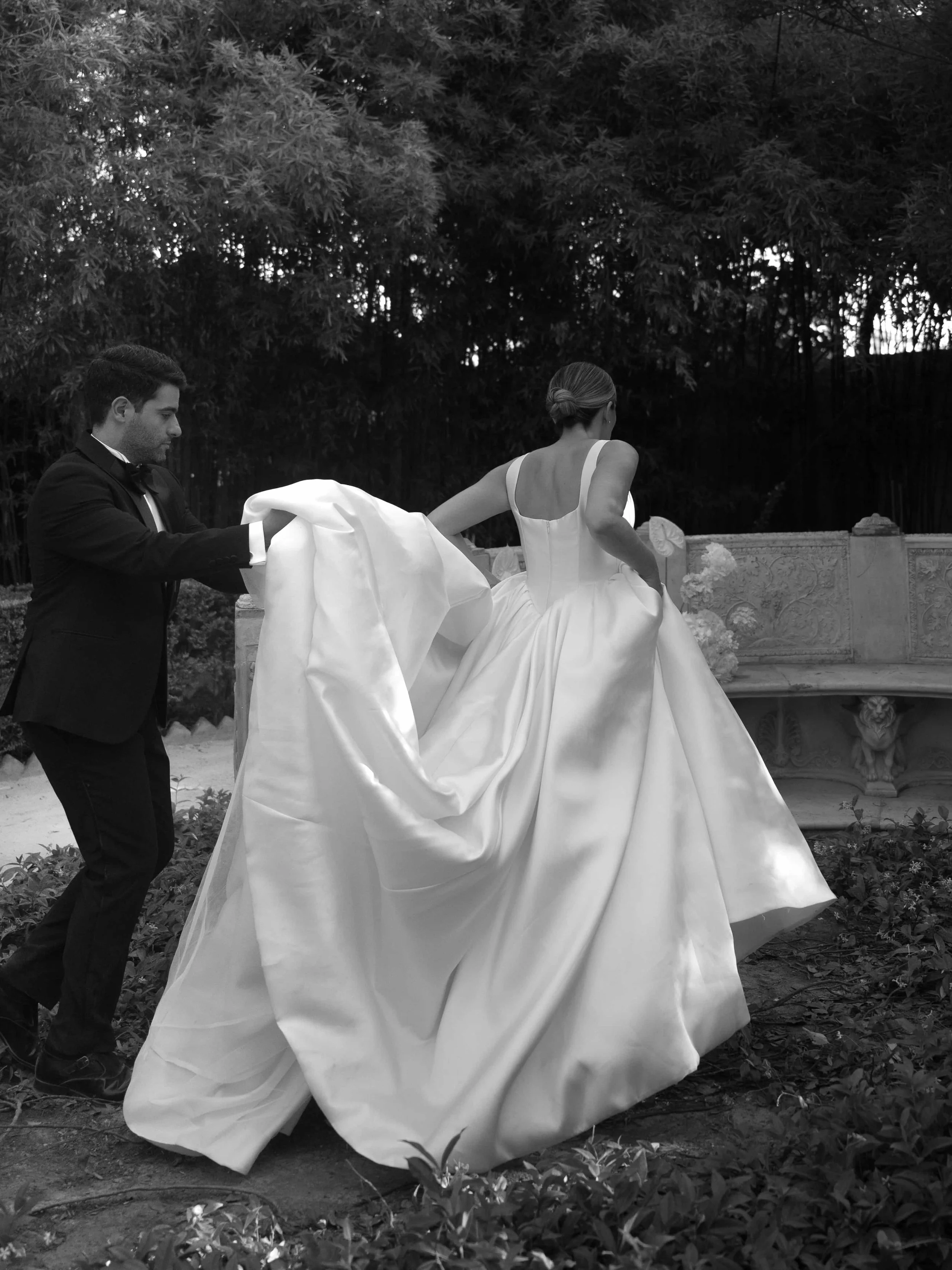 groom holding the bride's dress 