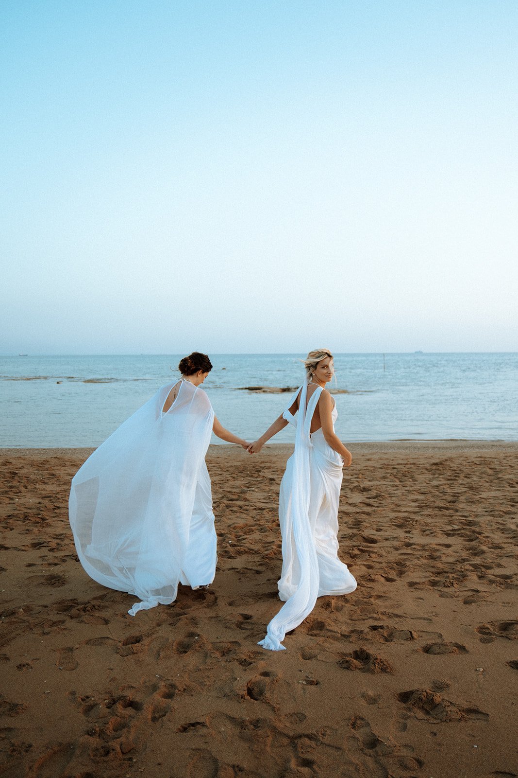 2 brides photoshoot on the beach running 