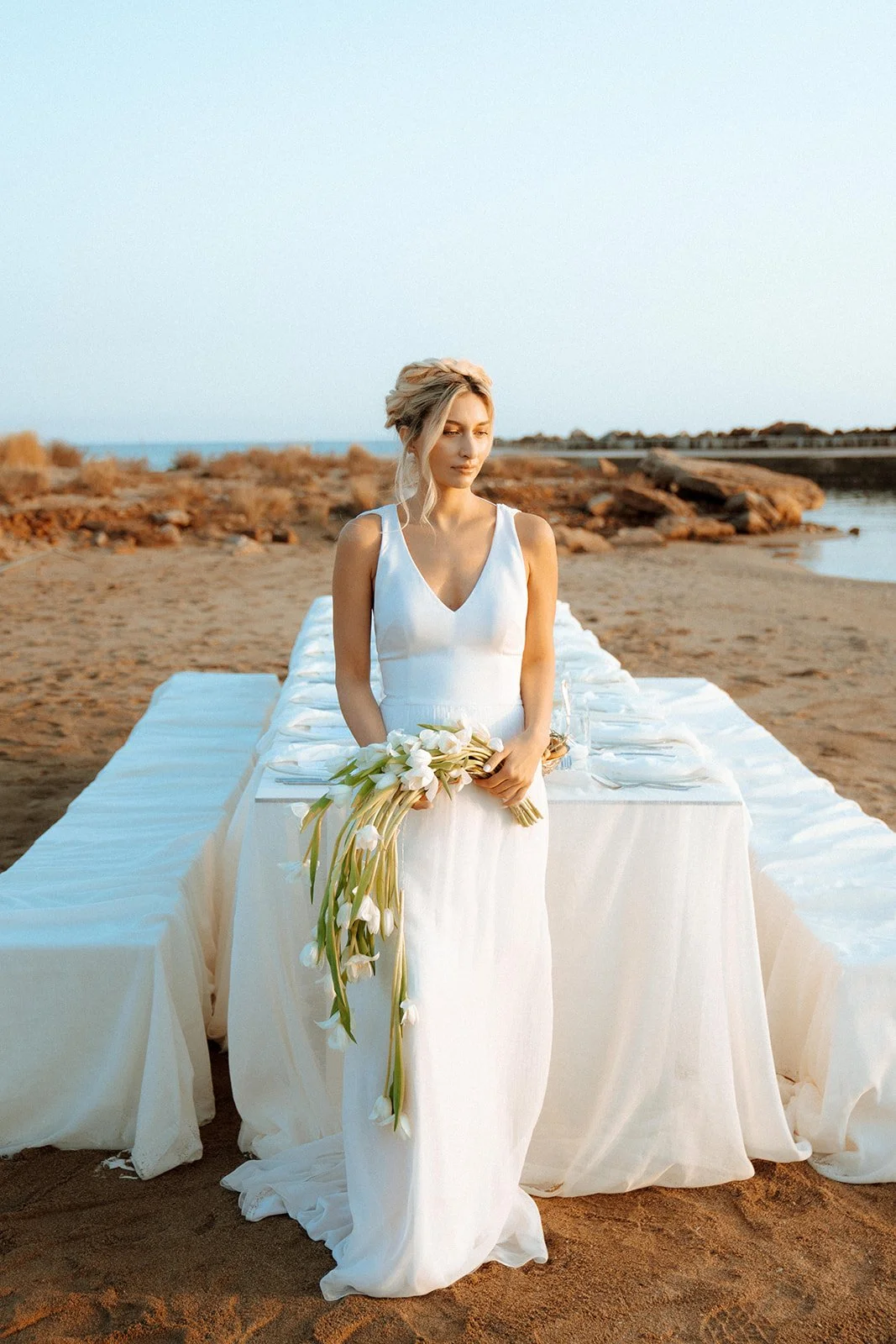 bride holding a tulip cascading bouquet in front of a wedding table setup 