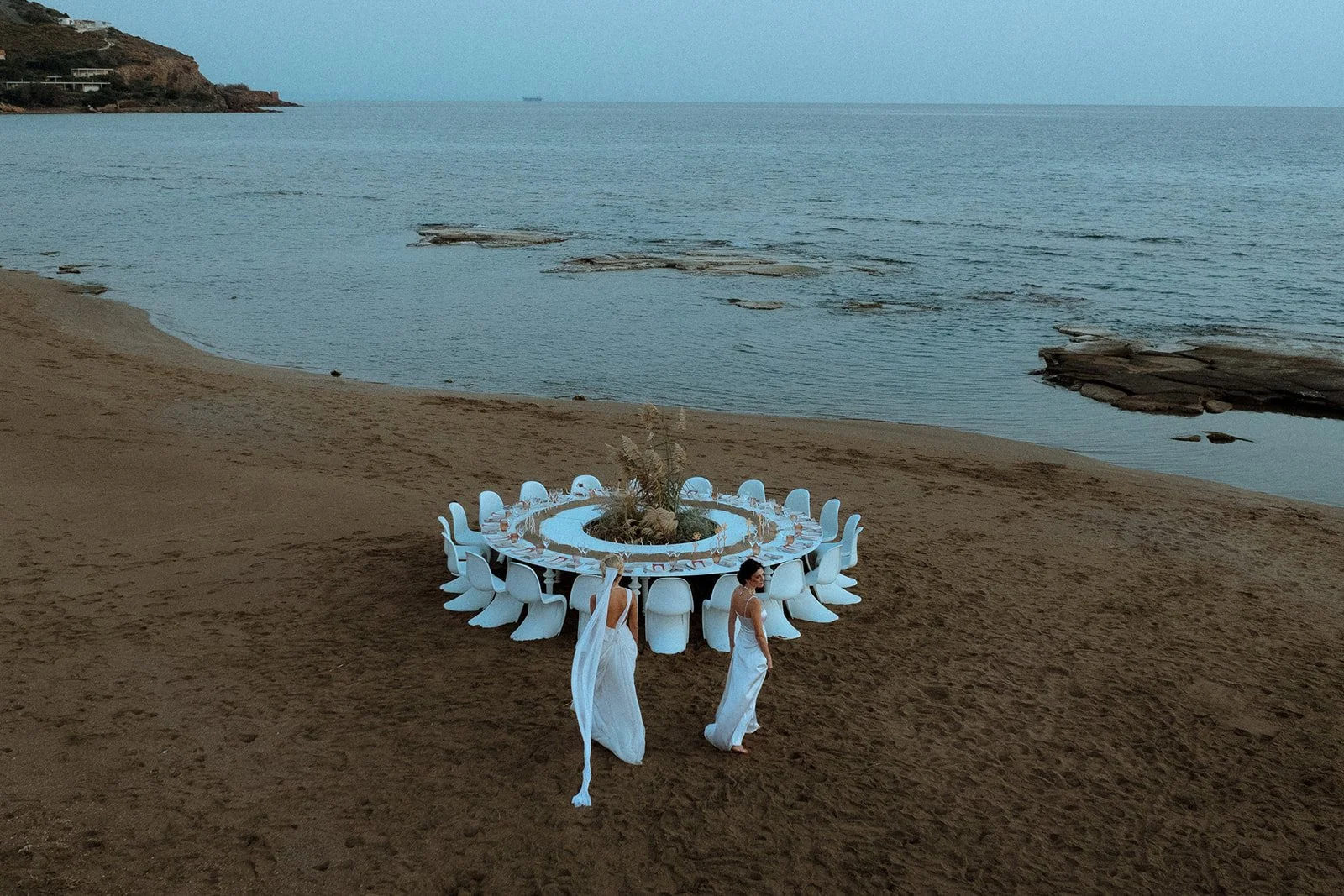 2 brides running around a round table on the beach